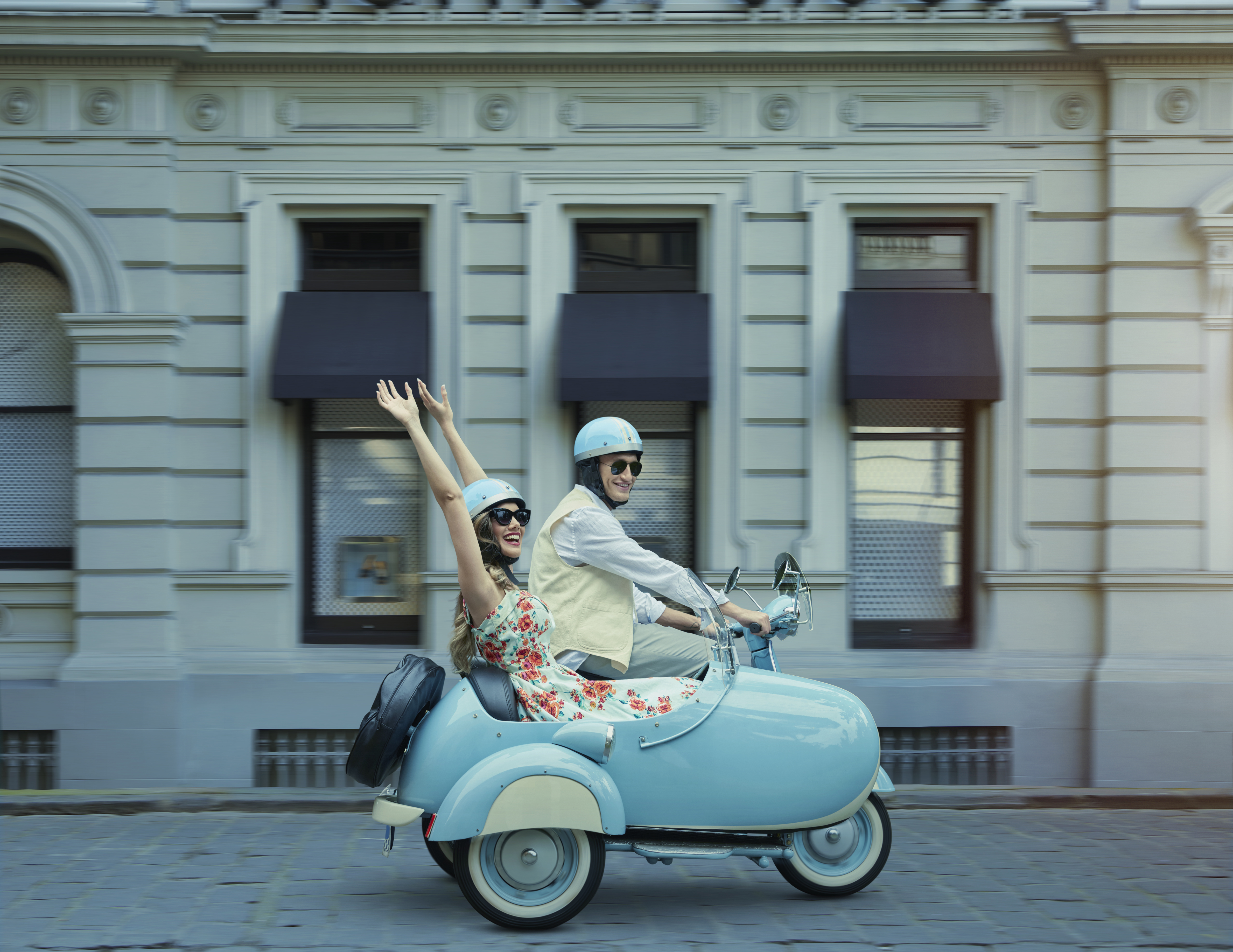 A excited woman sitting in a baby blue sidecar with her partner. | Source Getty Images