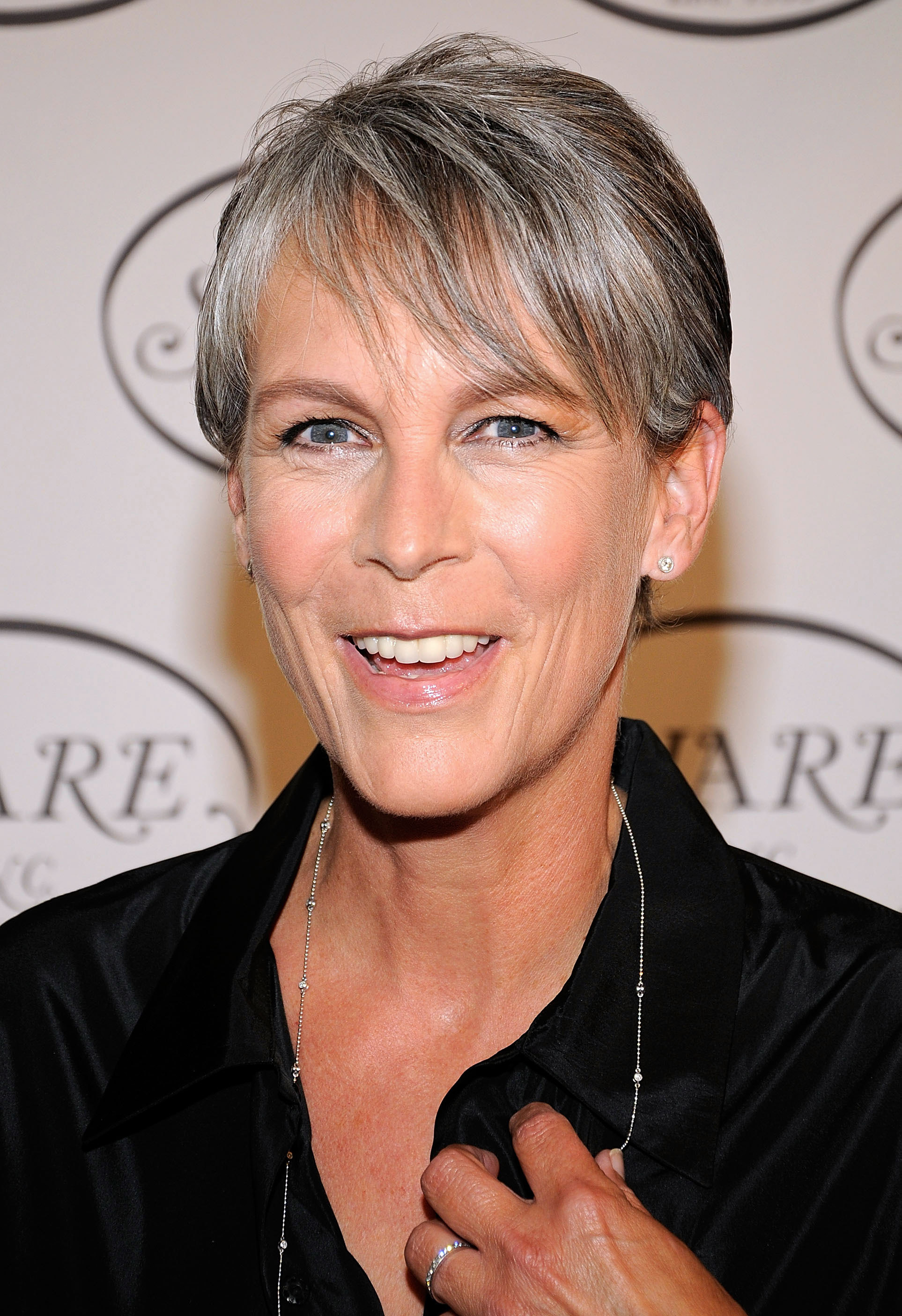 Jamie Lee Curtis lights up the red carpet at SHARE’s 57th Annual BOOMTOWN event, wearing a sleek black button-down and delicate chain necklace, her silver-blonde pixie cut adding a chic, modern edge.