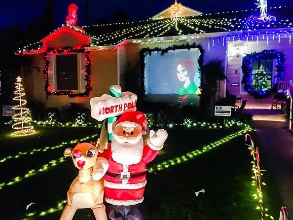 Santa and Rudolph the red nosed reindeer and a video screen projection are part of a private homes Christmas lights display on candy cane lane in El Segundo | Photo: Getty Images