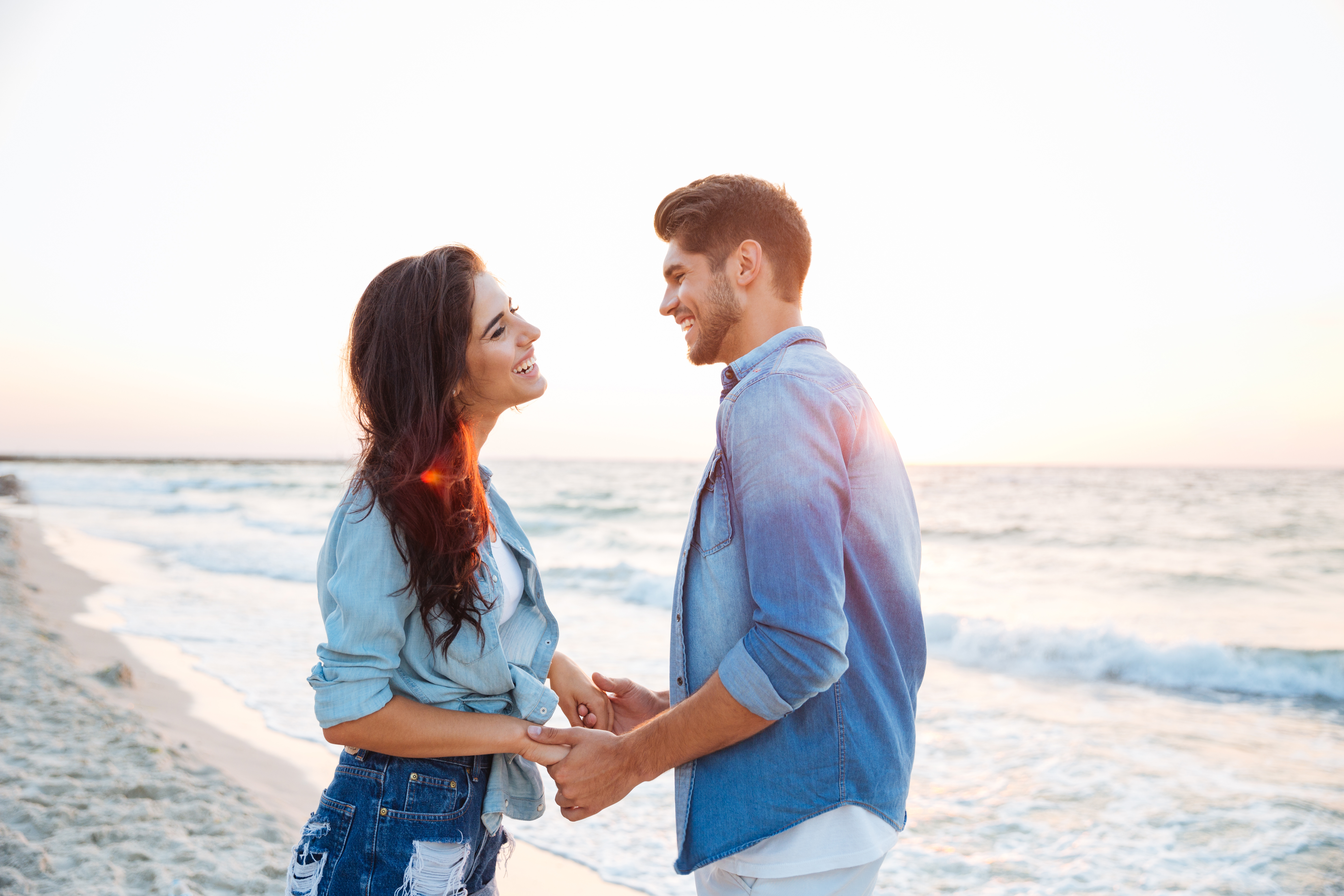 A happy couple walking and holding hands at the beach | Source: Shutterstock