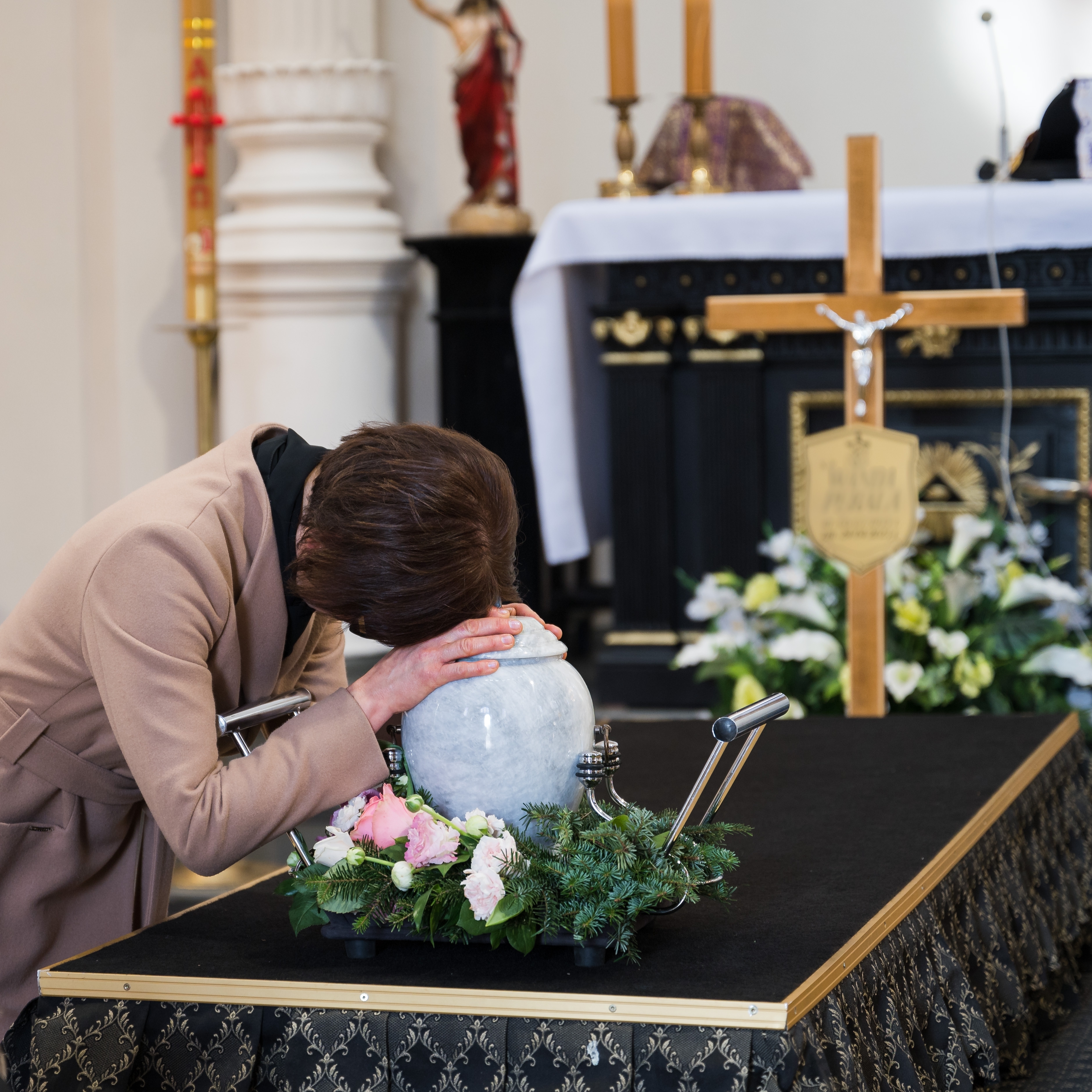 A woman crying over the urn of a loved one during a funeral | Source: Shutterstock