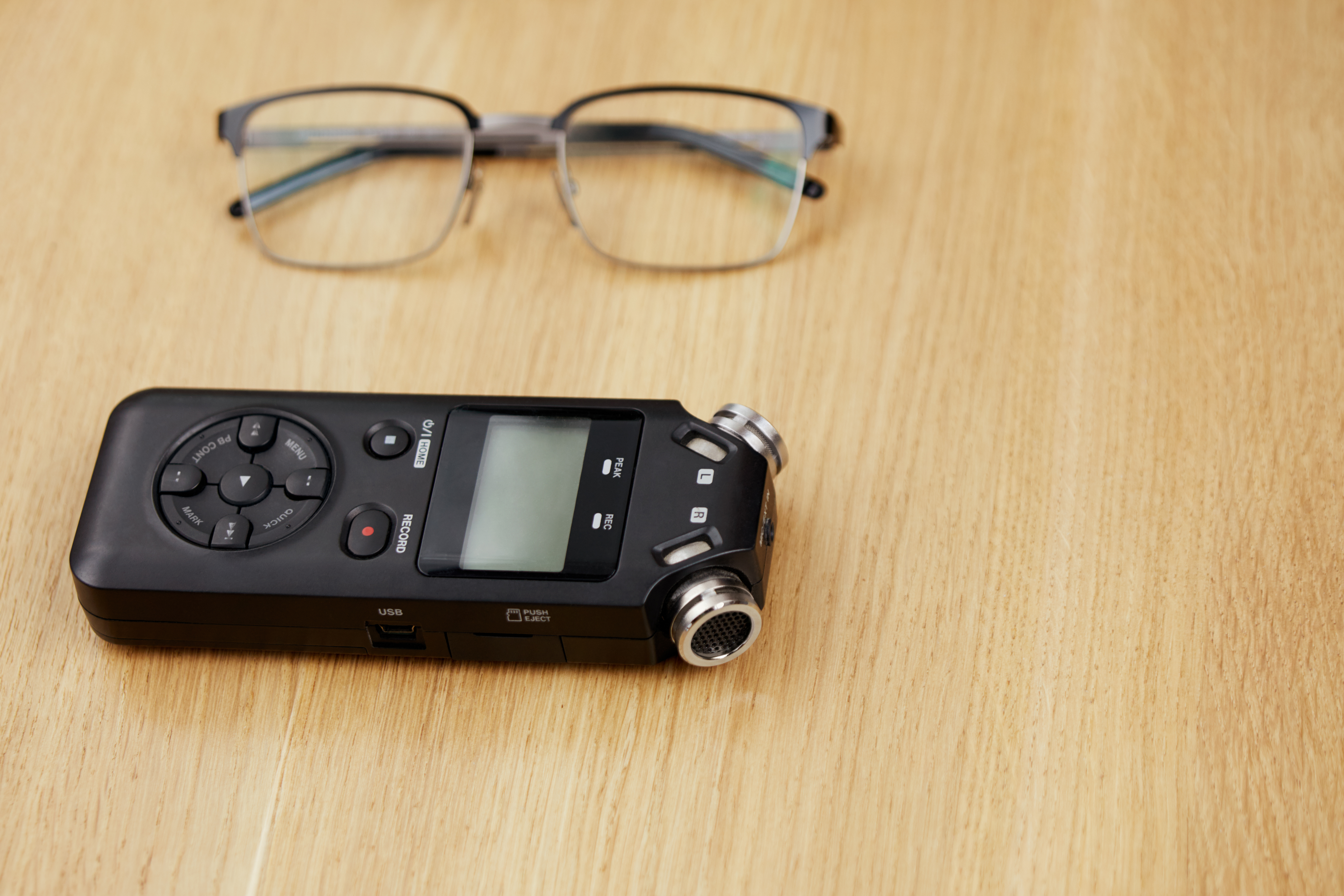 Audio recorder and spectacles lying on a table top | Source: Shutterstock