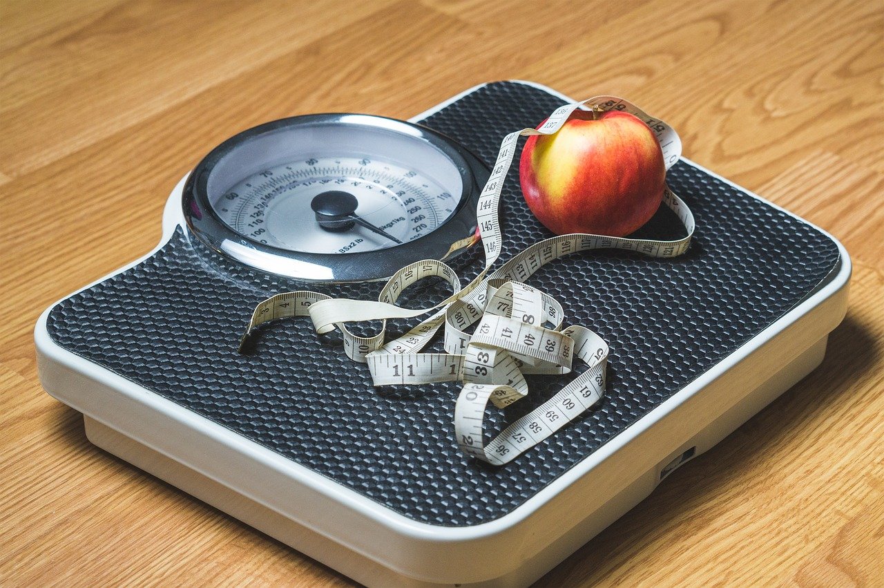 A photo of a scale, measuring tape, and an apple | Photo: Needpix/TeroVesalainen