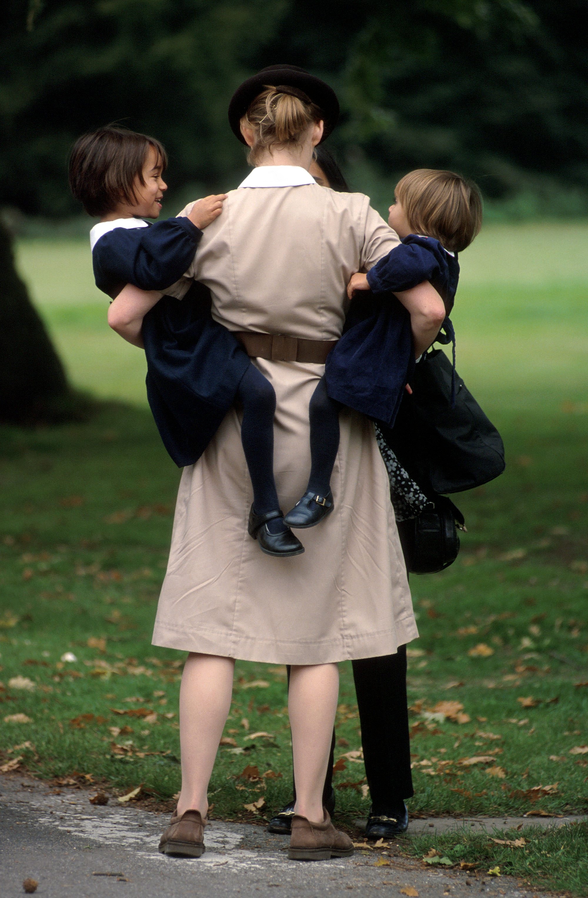A Norland Nanny carrying two of her charges in October 1999 | Source: Getty Images
