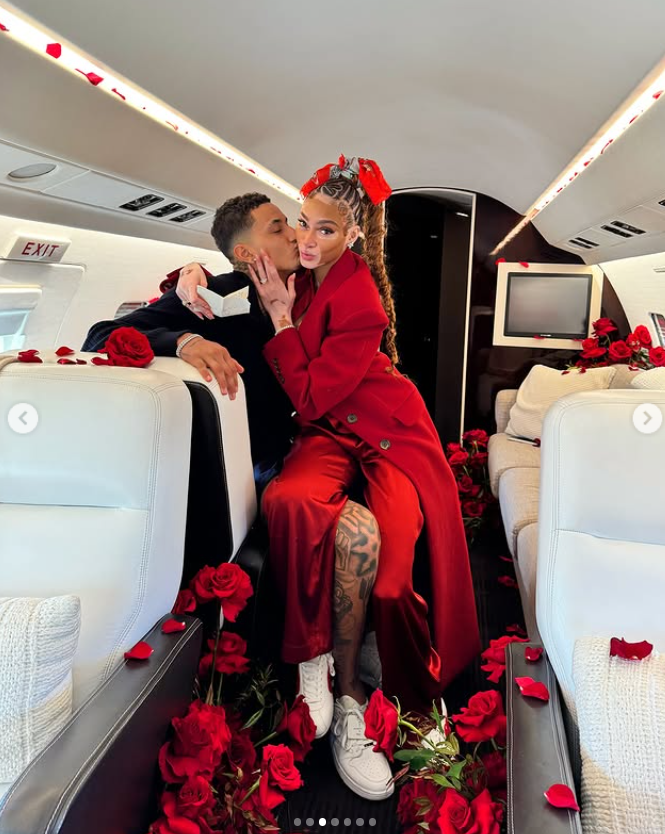 Kyle Kuzma kisses Winnie Harlow on the cheek as she poses confidently, with red rose petals scattered around them in the luxurious jet cabin | Source: Instagram/winnieharlow