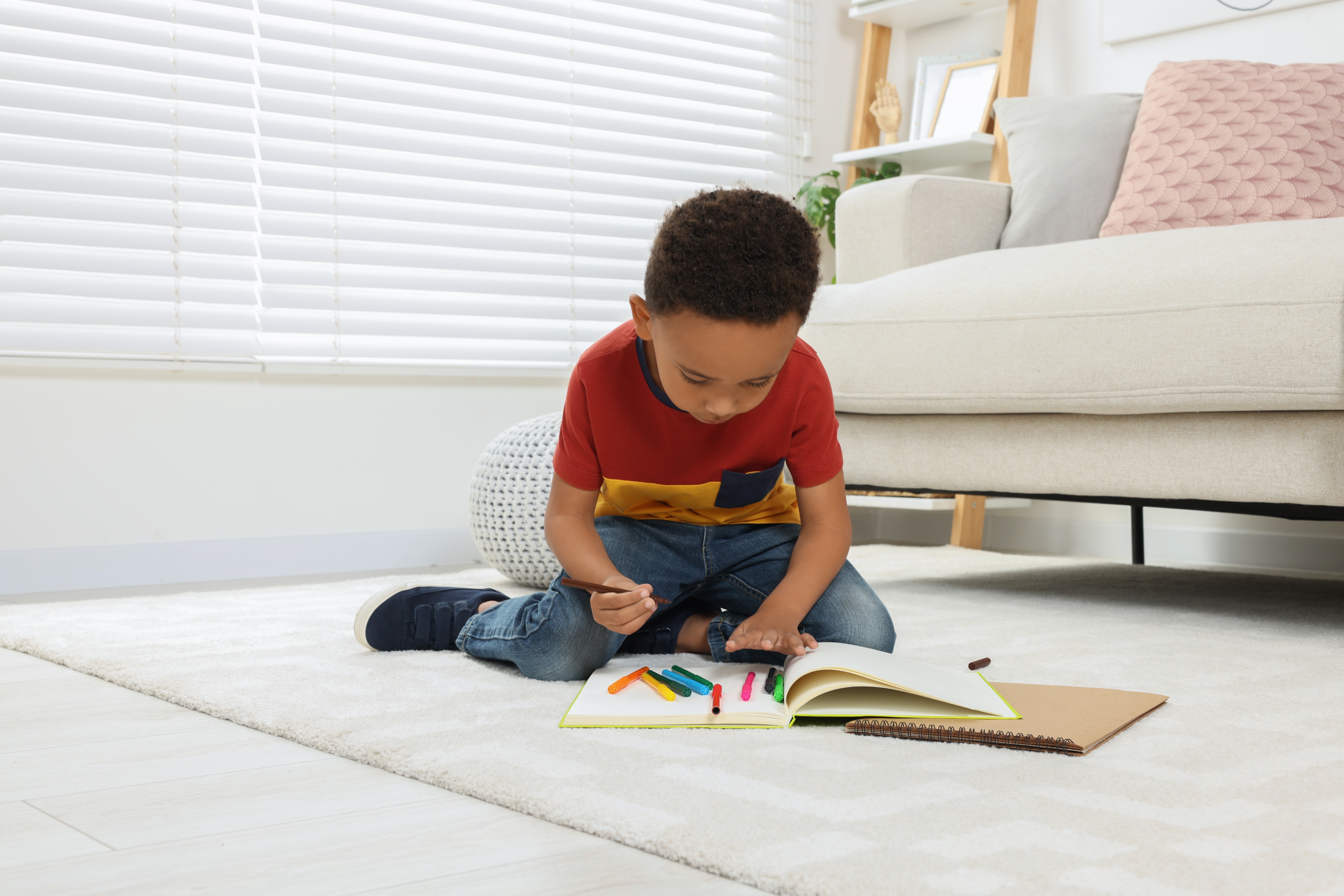 Little boy is drawing sitting on the floor | Source: Shutterstock.com
