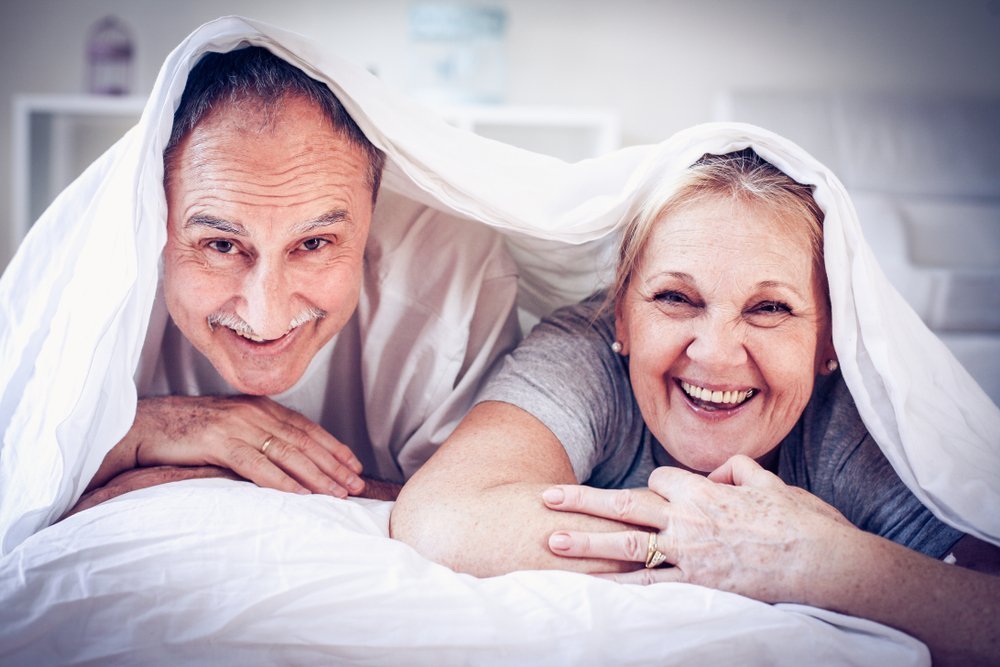 Elderly couple snoozing in bed | Shutterstock