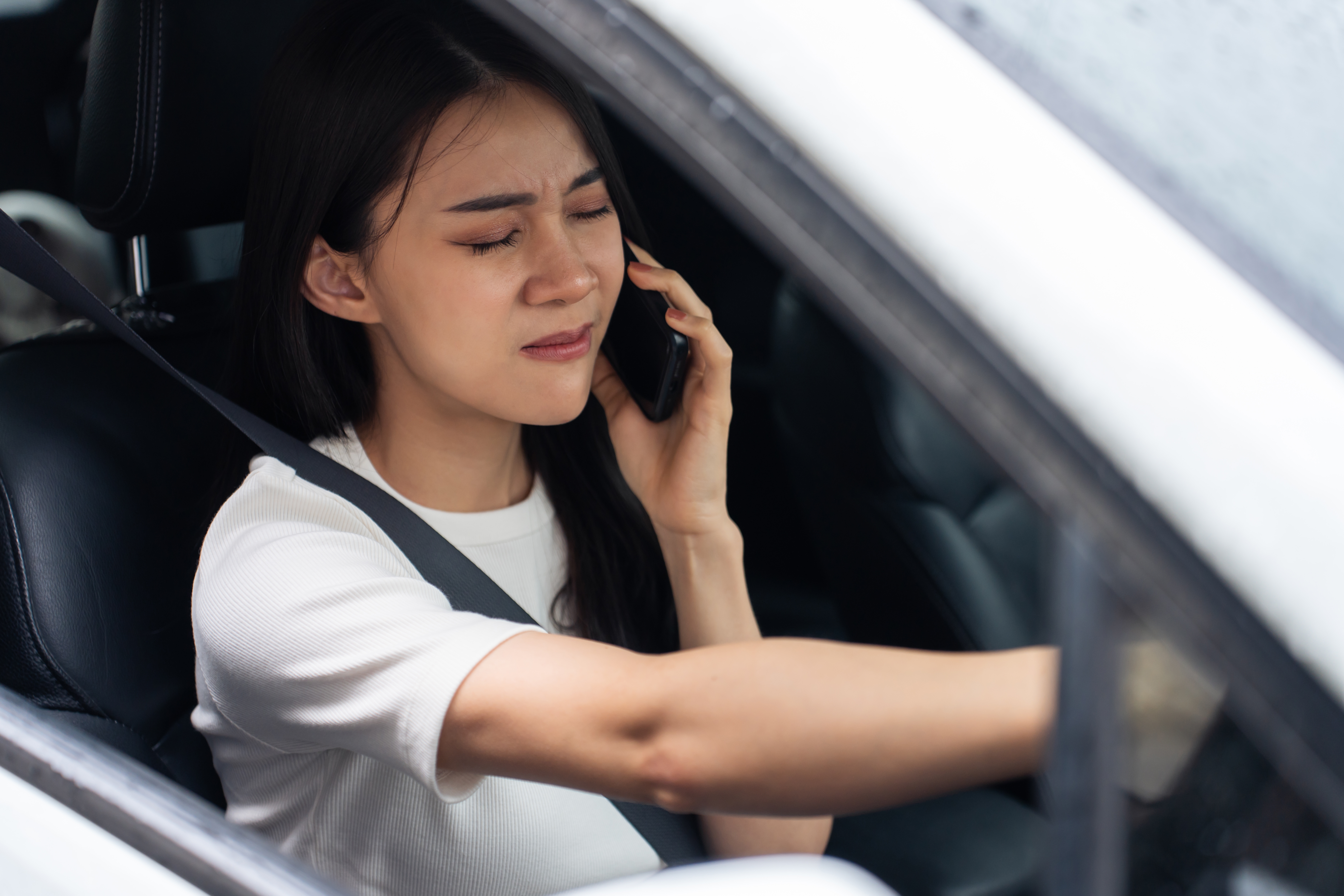 Beautiful woman talk on mobile phone while driving on the road | Source: Shutterstock.com