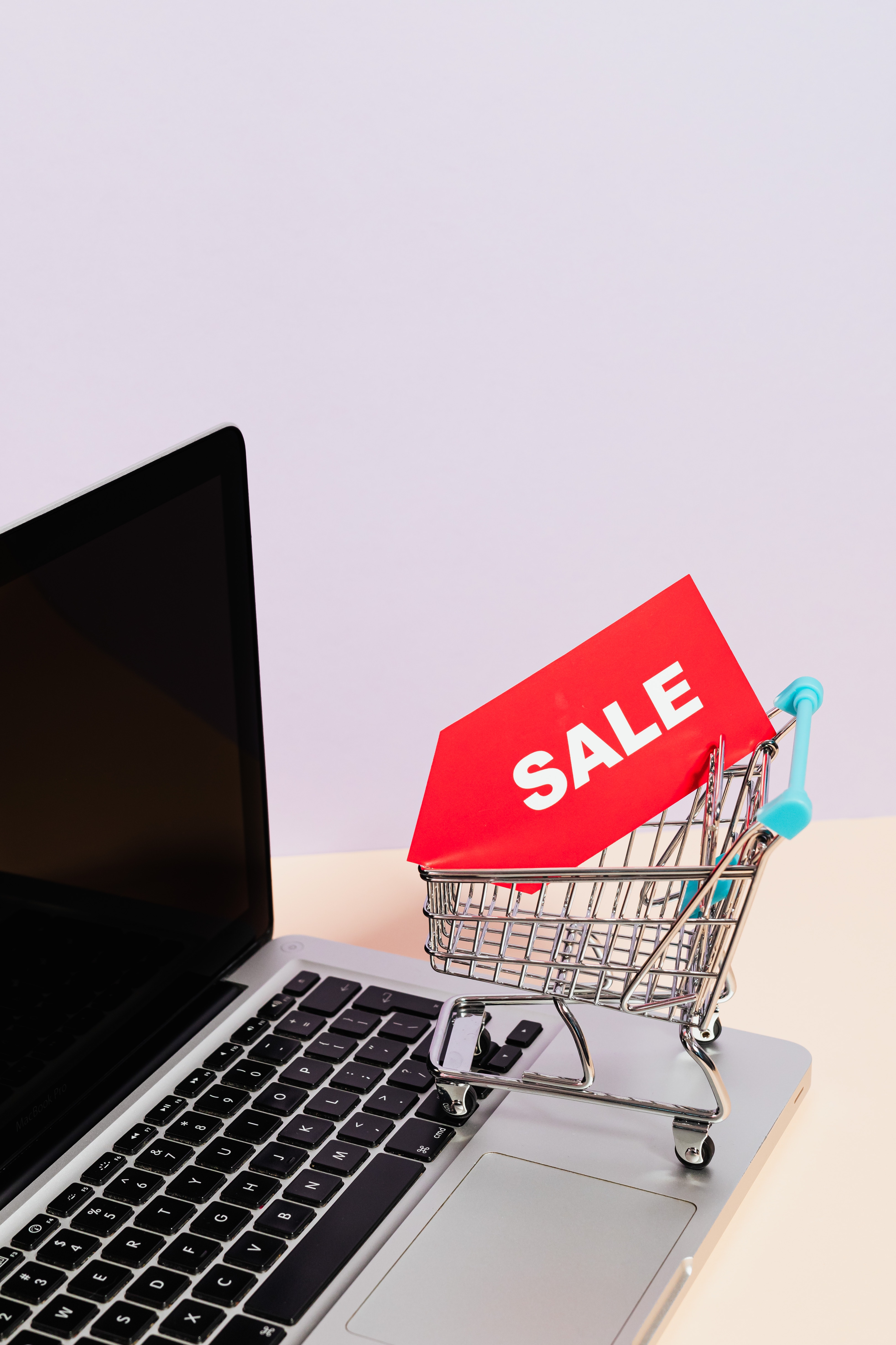 A red sale tag on a miniature shopping cart placed on a laptop | Source: Pexels