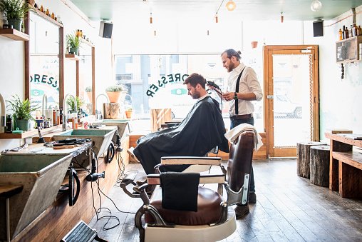 Un styliste caucasien coupe les cheveux d'un client chez le coiffeur. | Photo : Getty Images Un styliste caucasien coupe les cheveux d'un client chez le coiffeur. | Photo : Getty Images