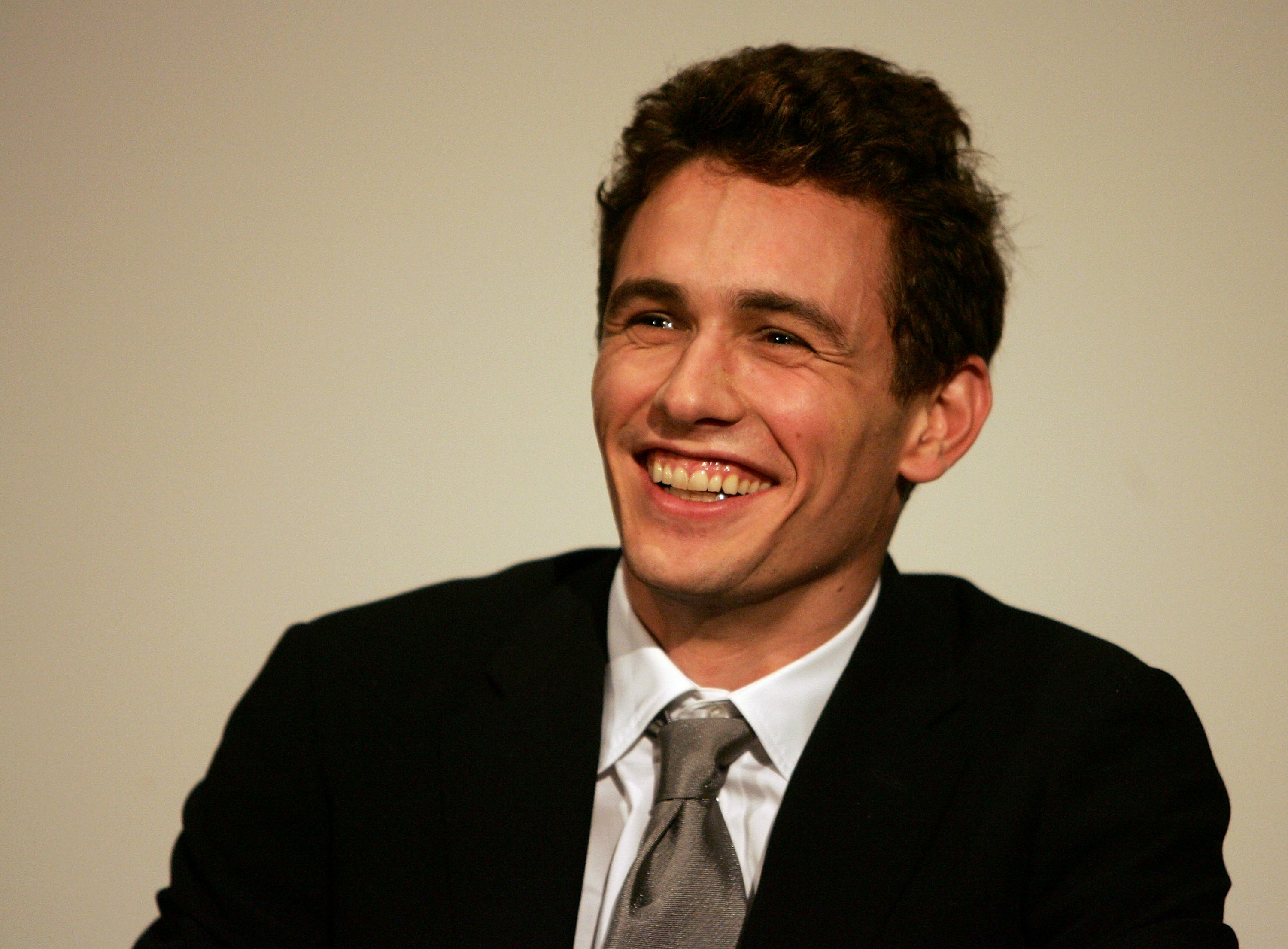 Dressed in a sleek black suit and gray tie, Franco beams during a film Q&A. His confident smile and charisma reflect his growing status in Hollywood at the height of his early fame.