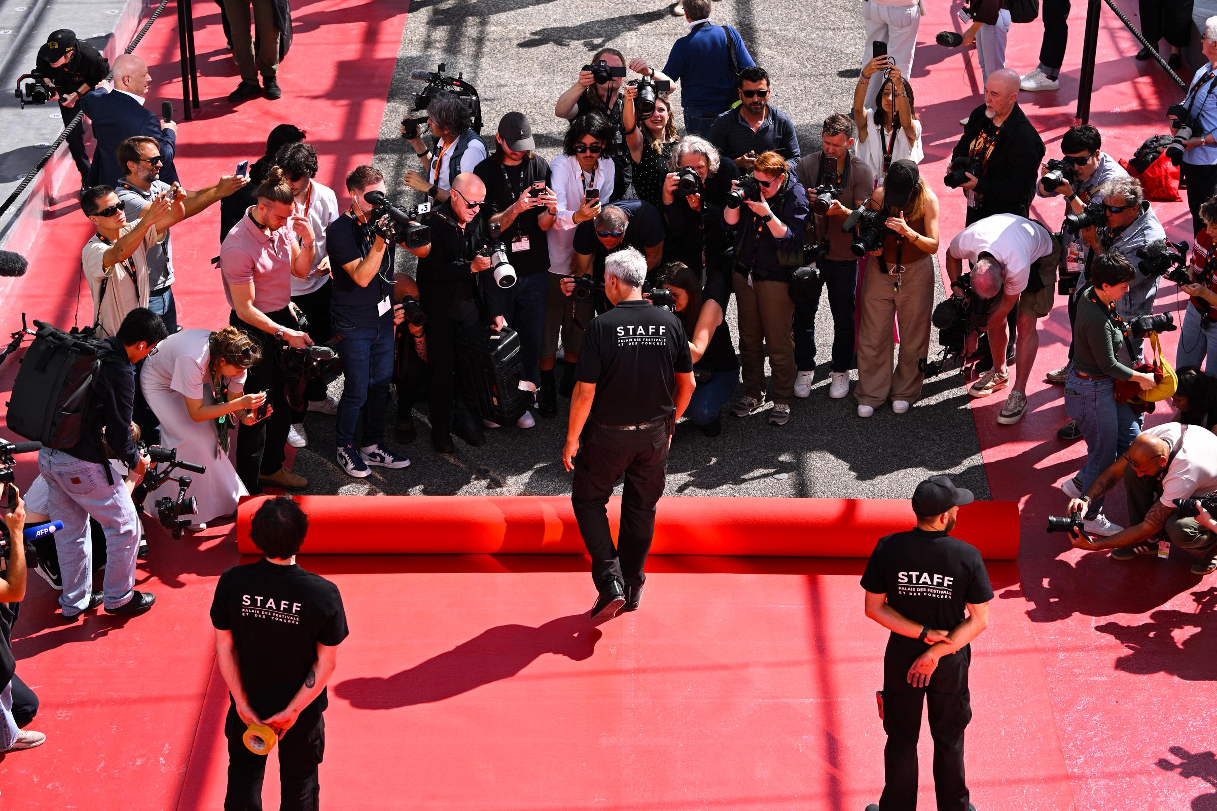 An employee unrolls the red carpet on the stairs of the Palais des Festivals ahead of the opening ceremony of the Cannes Film Festival on May 12, 2026, in Cannes, France | Source: Getty Images