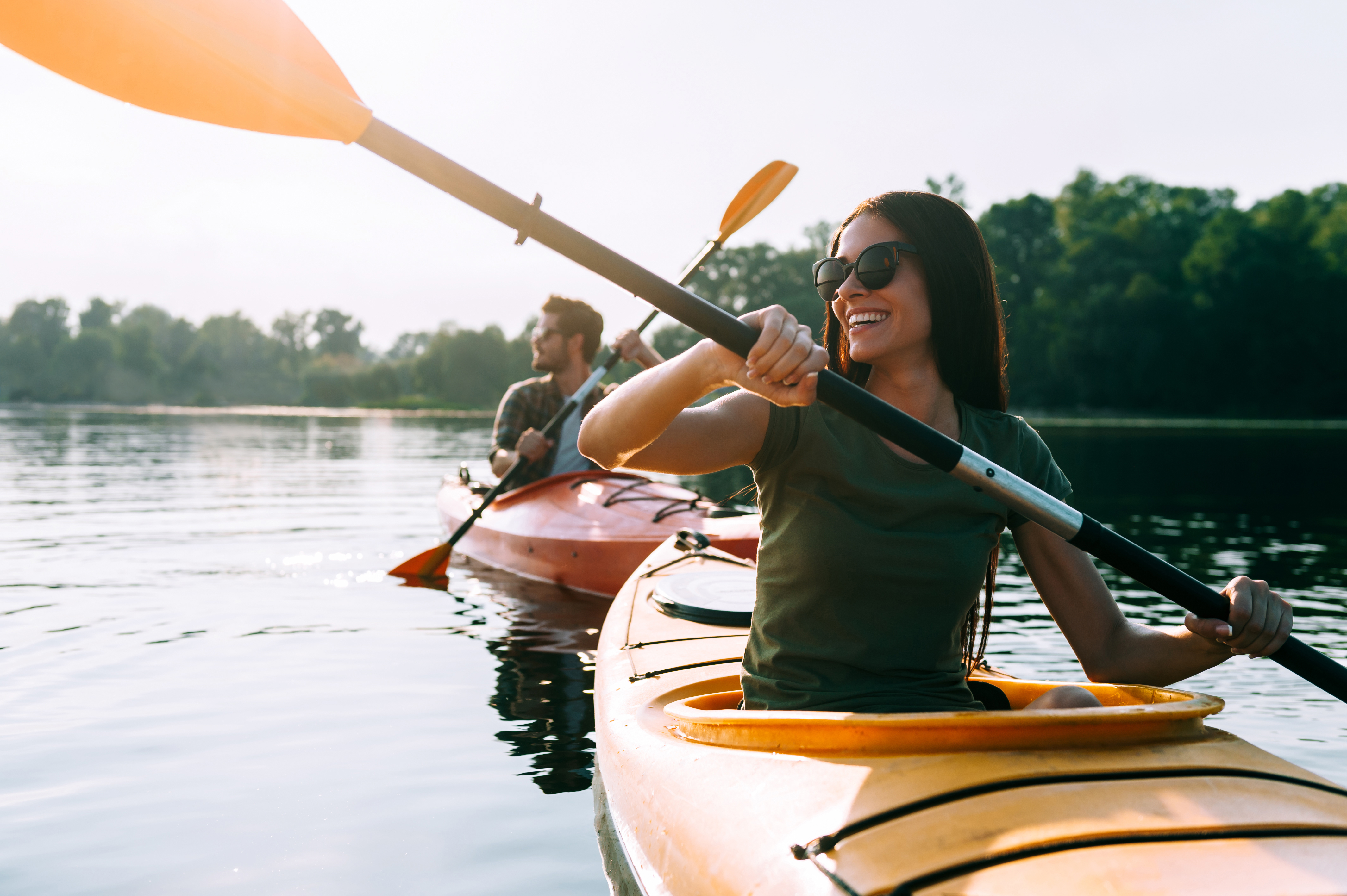 A young couple kayaking on the lake together and smiling | Source: Shutterstock
