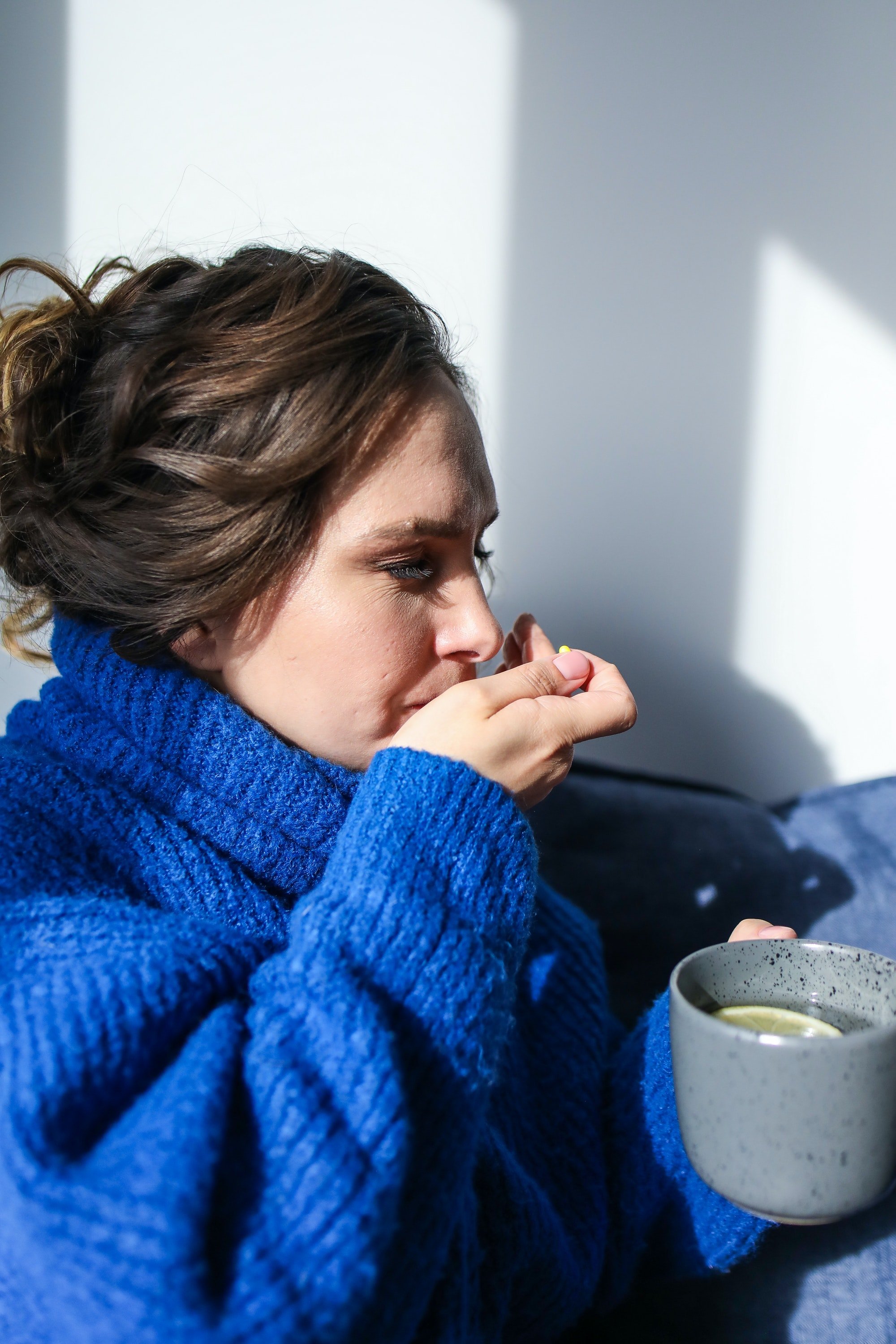 Mujer enferma tomando medicina y un té. | Foto: Pexels