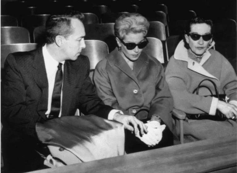 L'actrice américaine Lana Turner (C), portant des lunettes de soleil noires, est assise à côté de son ex-mari, Stephen Crane, dans une salle d'audience pendant le procès pour meurtre de leur fille, Cheryl Crane. Crane, qui avait poignardé l'ex-petit ami gangster de Turner, Johnny Stompanato, a été acquitté pour homicide justifié.1958. | Source : Getty Images