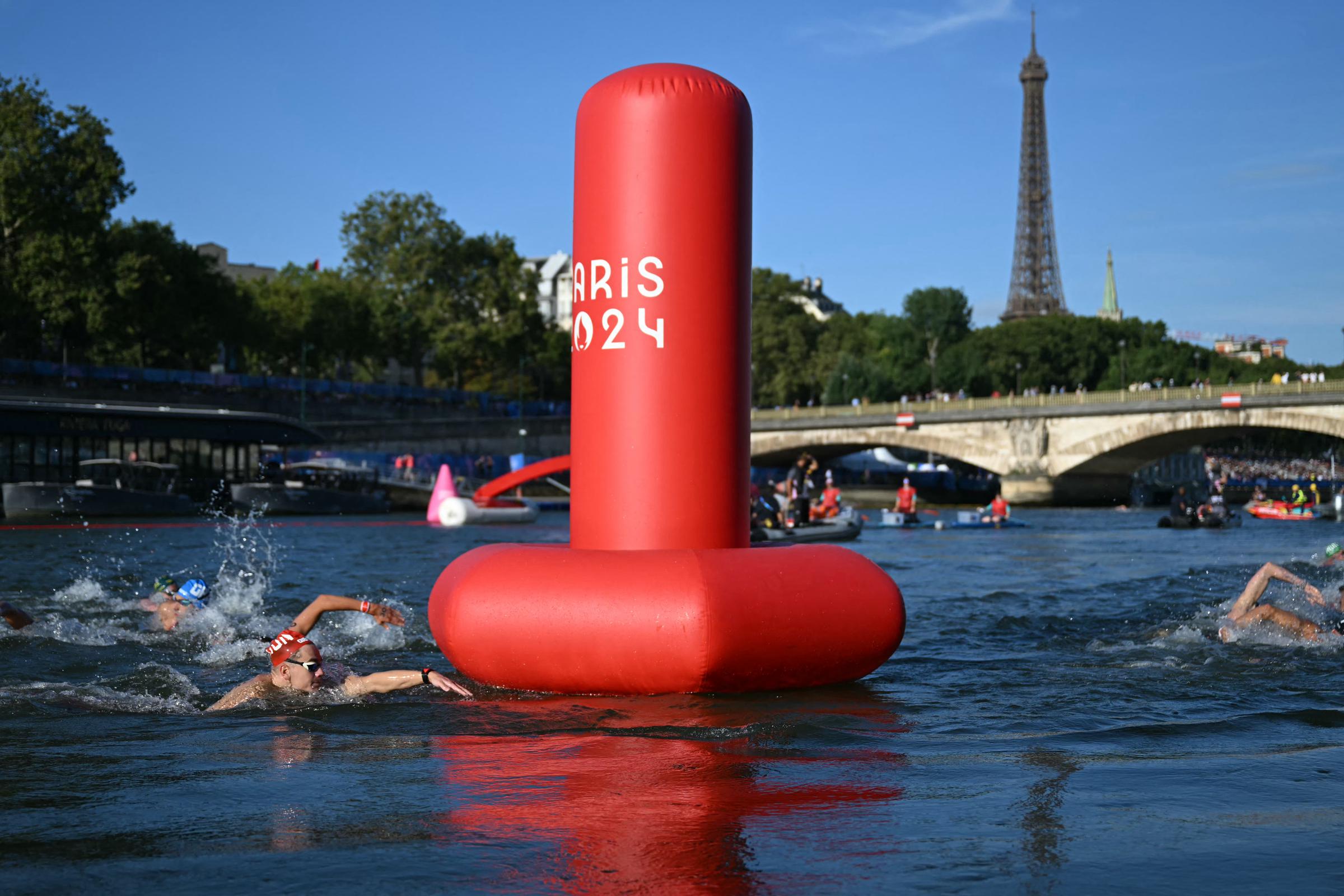 Athletes swim in the Seine River past the buoy during the men's 10km marathon swimming final at the Paris 2024 Olympic Games in Paris, on August 9, 2024 | Source: Getty Images