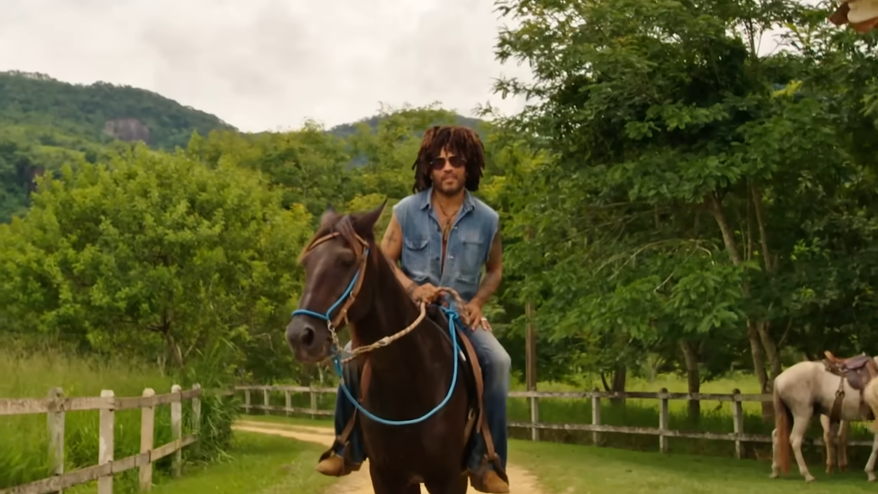 Clad in a sleeveless denim shirt and aviator sunglasses, Lenny looks completely at home navigating his massive countryside property. | Source: YouTube/@Archdigest