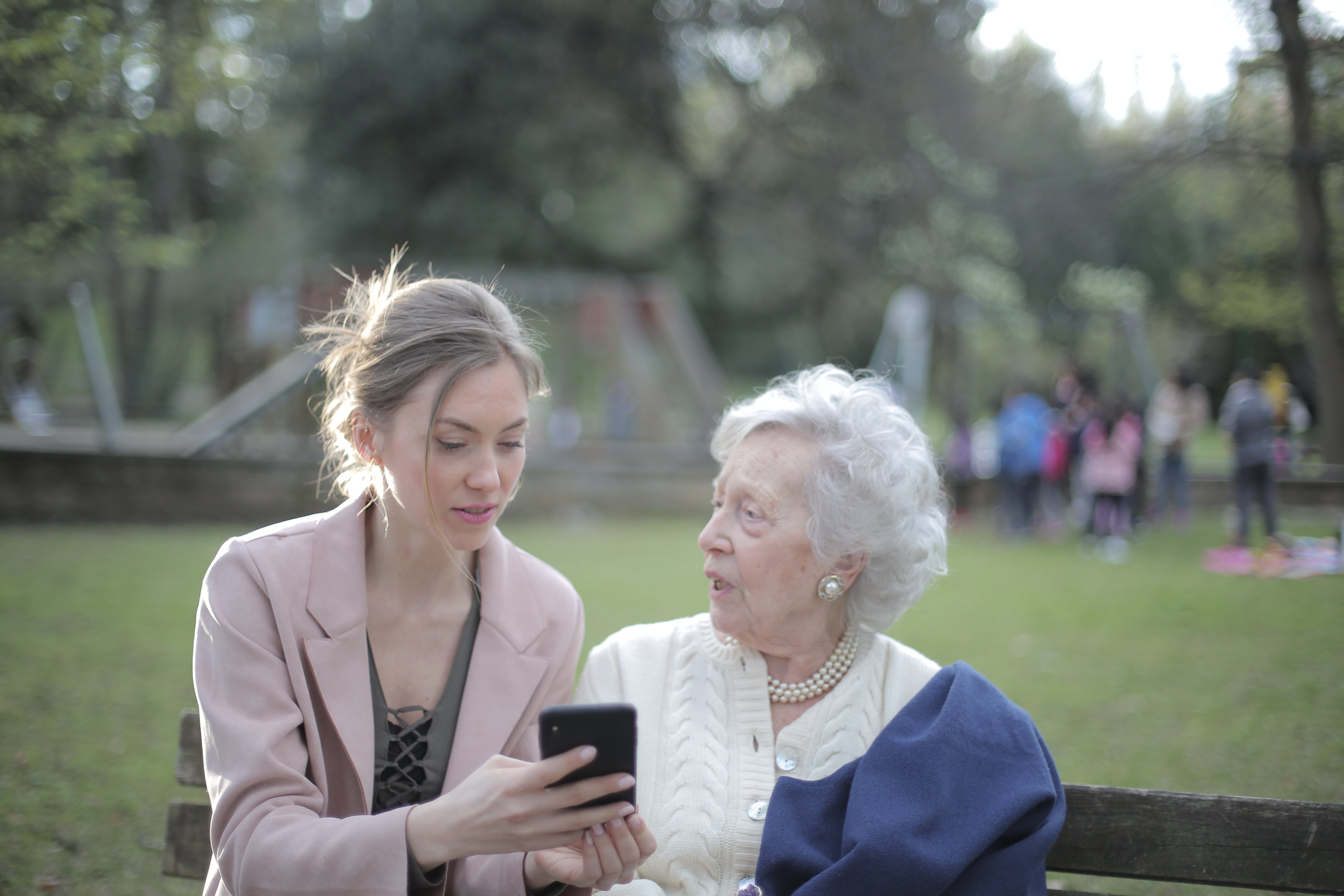 A younger woman showing an older one something on her phone while outside | Source: Pexels