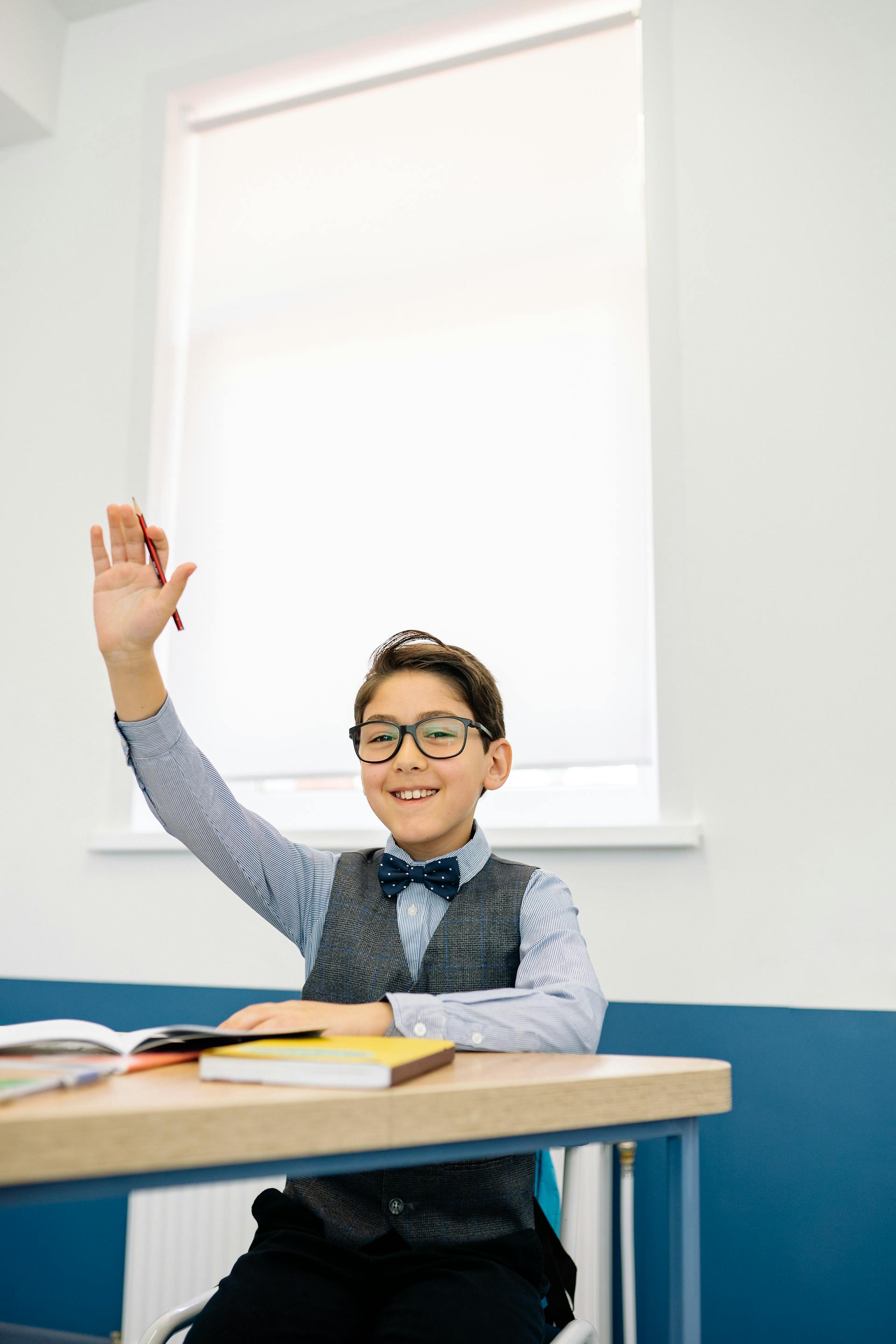 A young boy raising his hand in a classroom | Source: Pexels