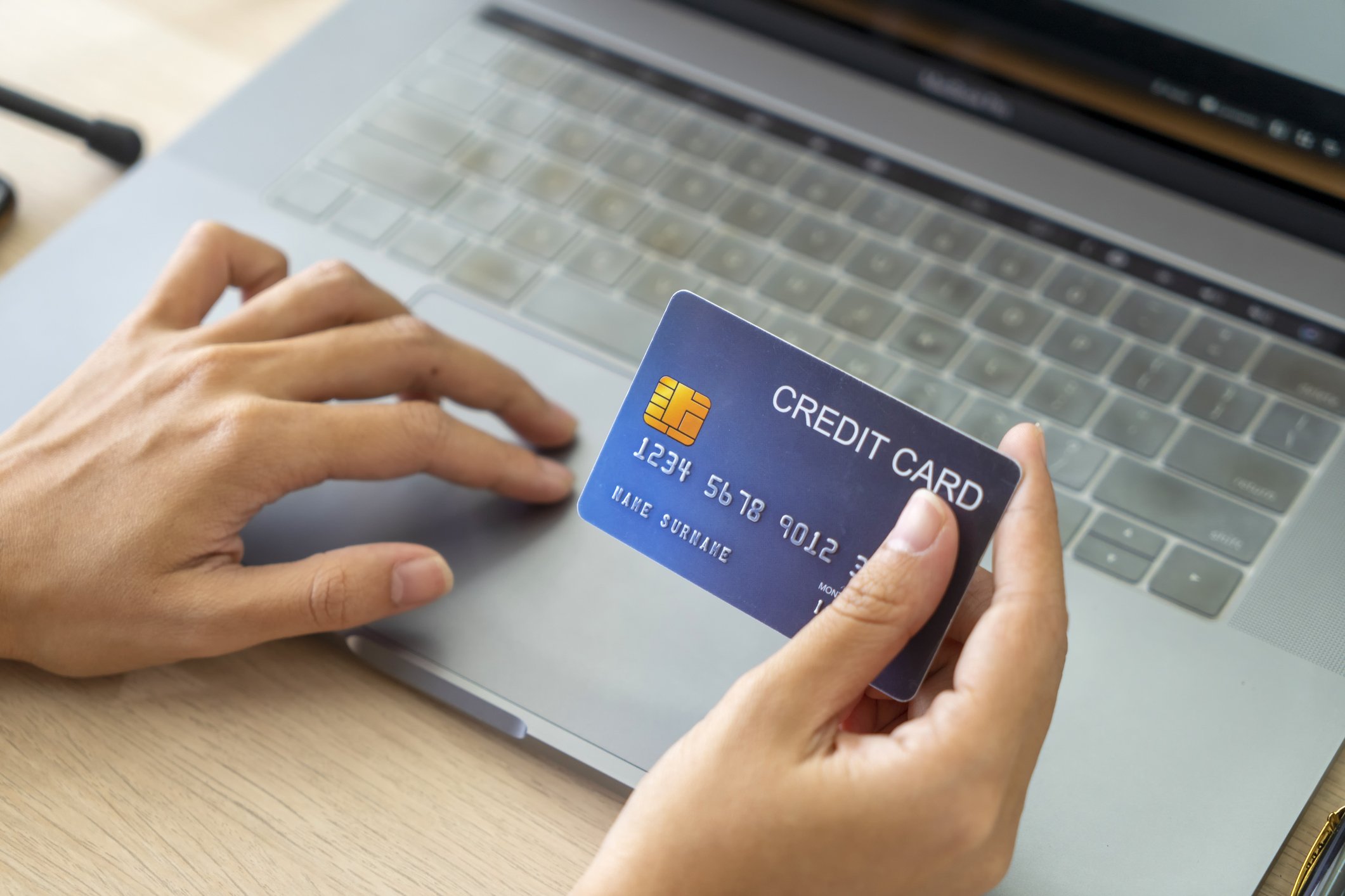 Hand, die Kreditkarte hält und Laptop verwendet. Geschäftsfrau oder Unternehmer, die von zu Hause aus arbeiten | Quelle: Getty Images