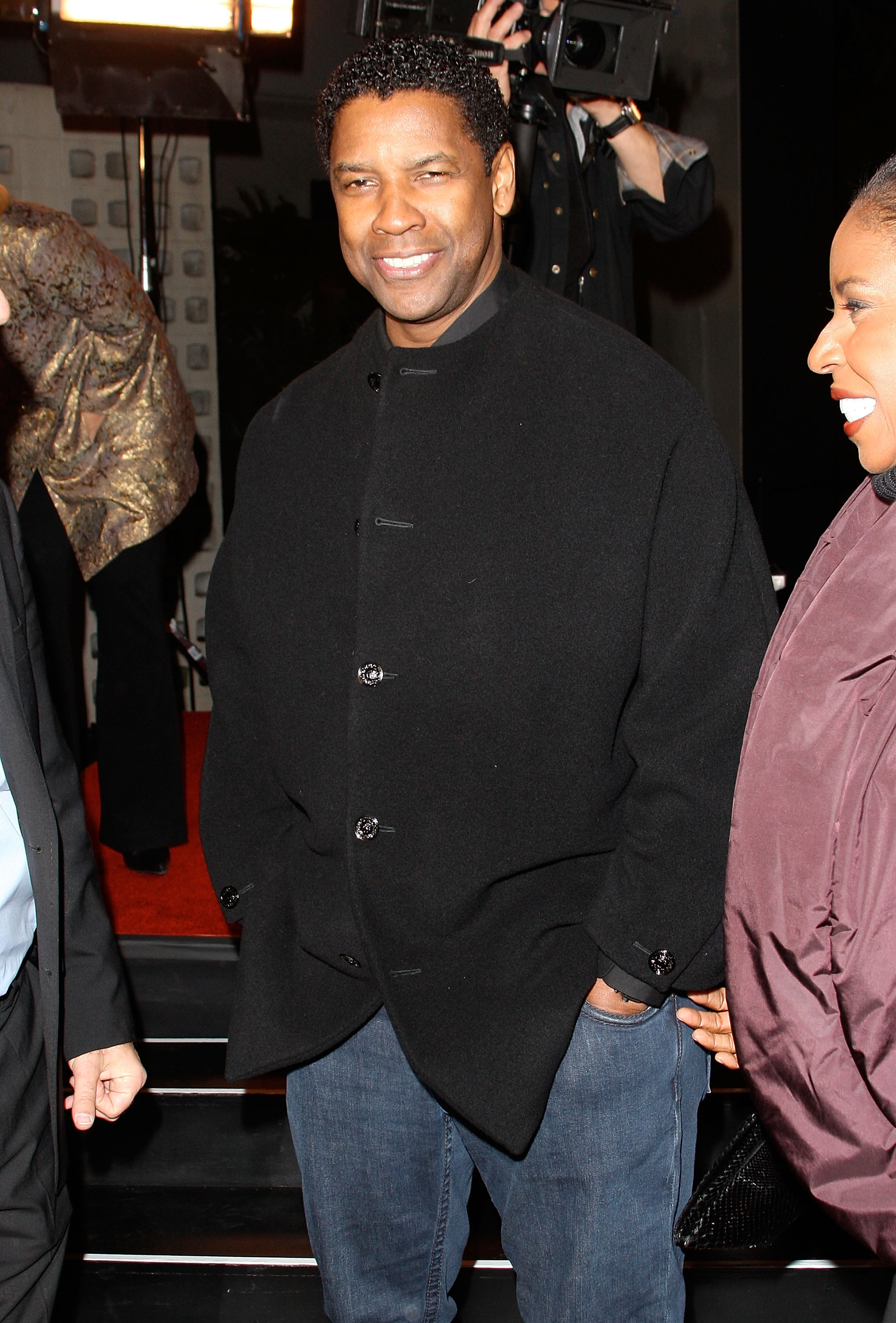 Denzel Washington smiles at the premiere of "The Great Debaters" in Hollywood. With a defined hairline and soft curls, his style is relaxed yet refined, complementing his understated black wool coat and jeans.