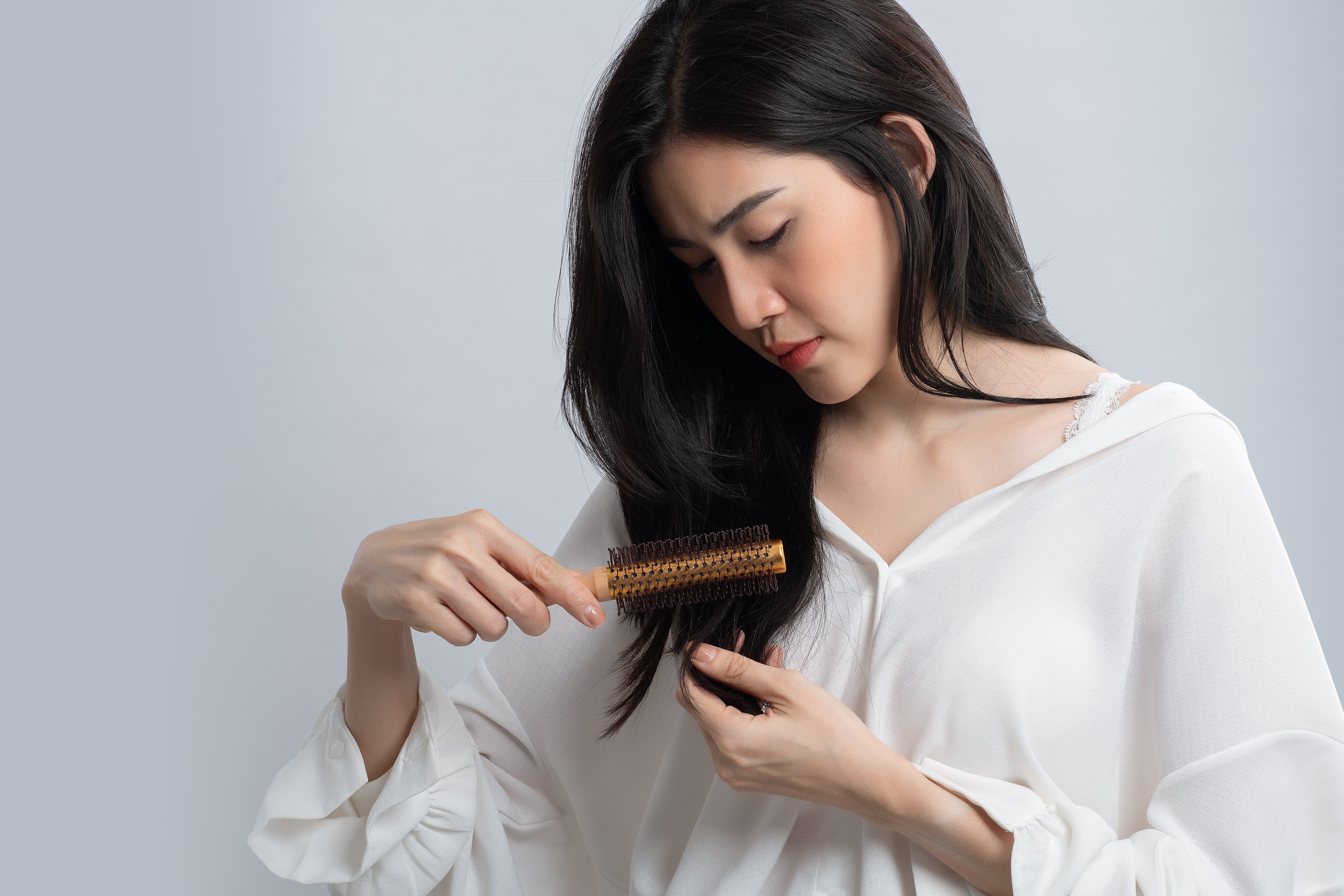 Portrait d'une femme asiatique aux cheveux longs avec un peigne et des cheveux. | Photo : Shutterstock