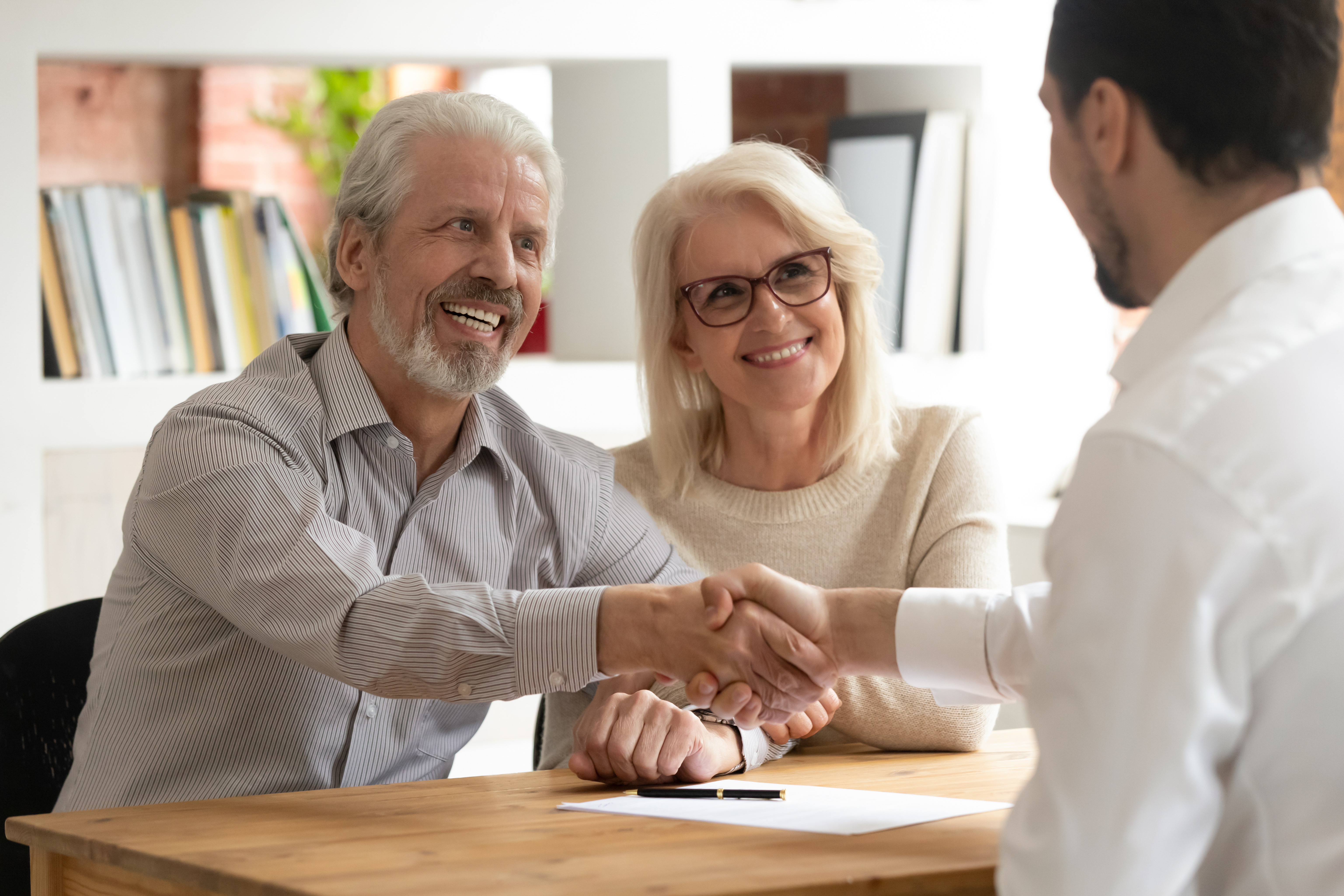 An older couple congratulating a younger man after signing paper work | Source: Shutterstock