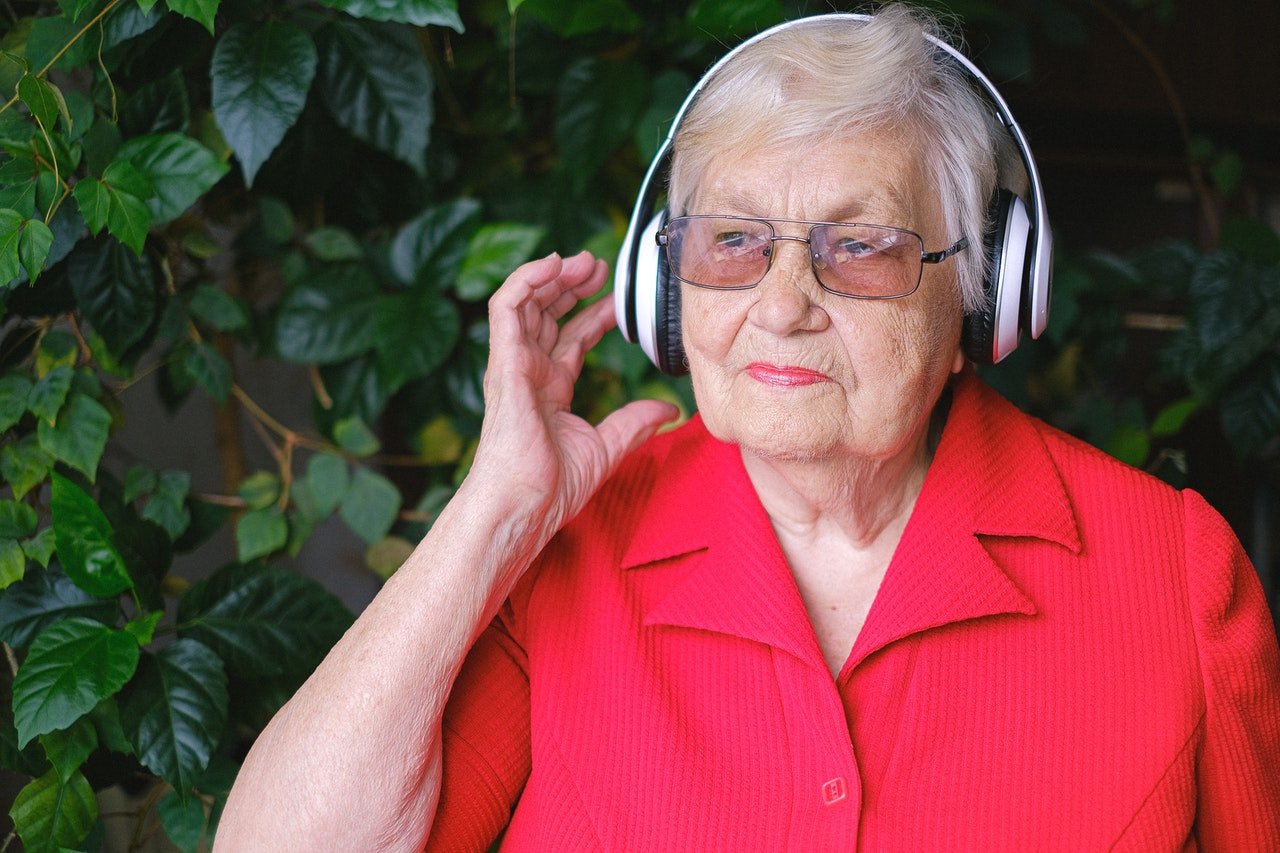 Mujer anciana usando auriculares. │Foto: Pexels