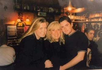 Collins, left, radiates easy warmth in this candid pub shot from her earlier years, flanked by family and looking every bit the social force she would later become on national television. The warm glow of the bar behind them gives it the feel of a night that nobody wanted to end. | Source: Instagram/gemmacollins