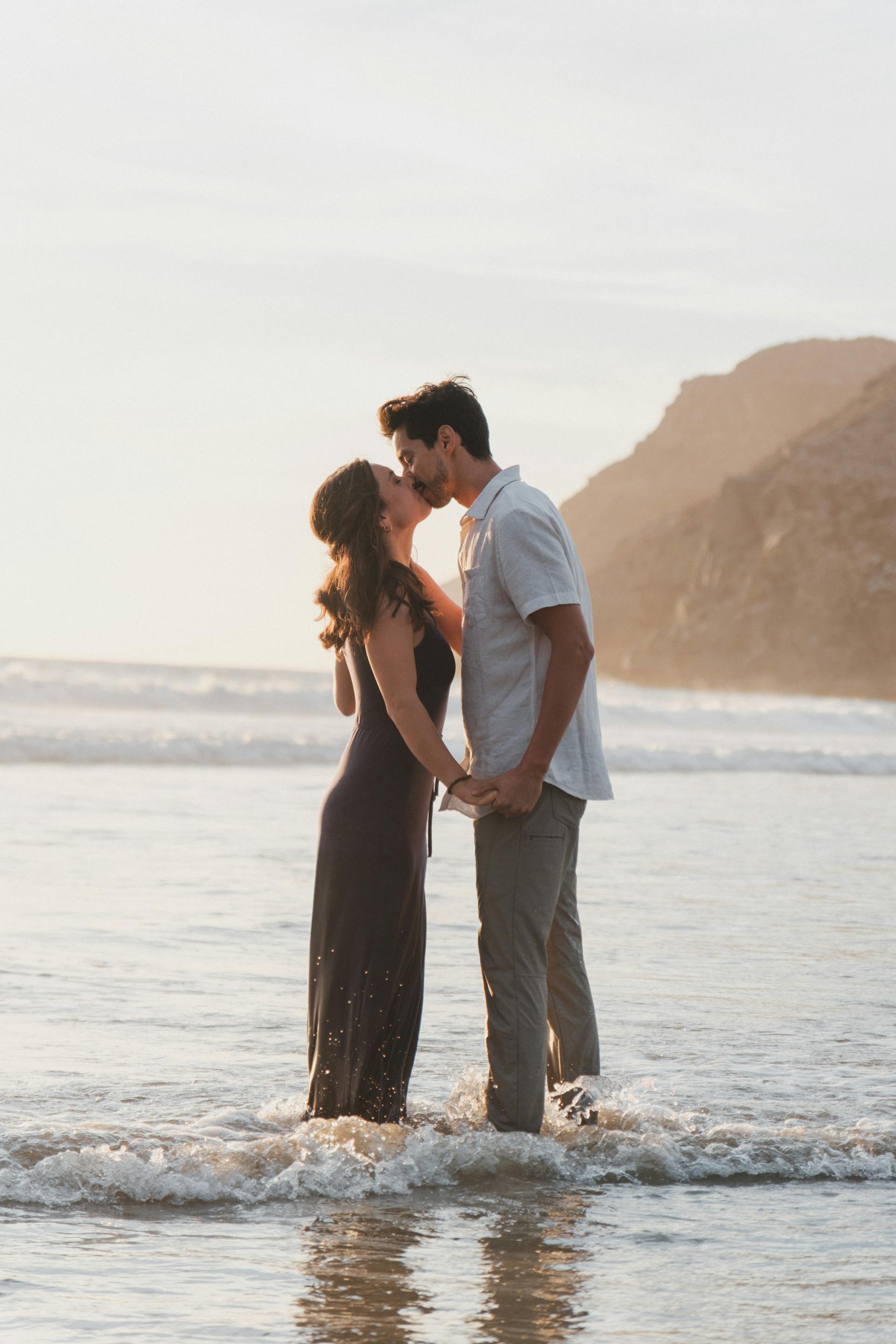 A couple kissing while standing ankles deep in the sea | Source: Pexels