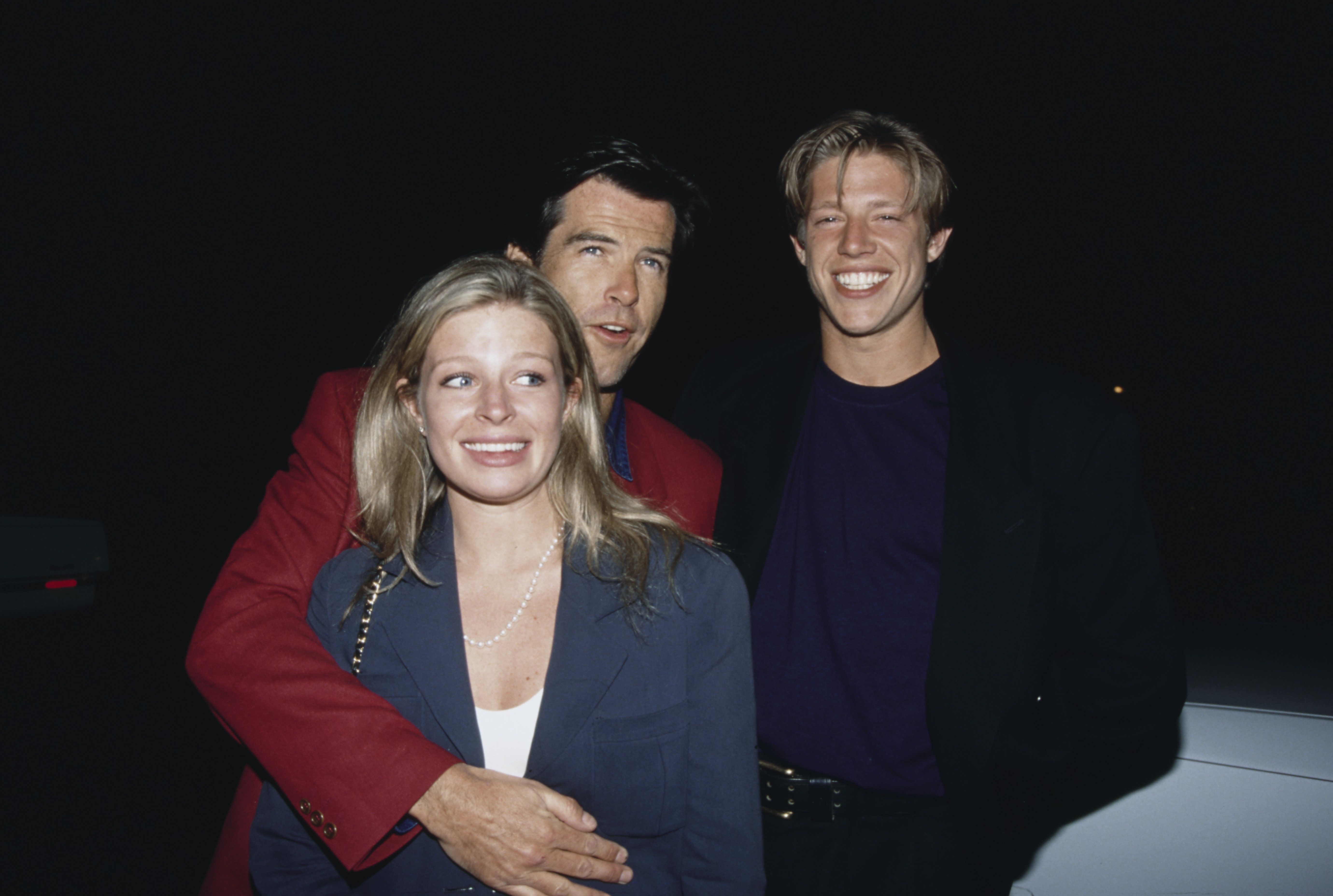 Irish actor Pierce Brosnan kisses his adopted daughter Charlotte Harris (1971-2013) alongside Harris' partner, American entertainer Alex Smith, at an after party, held at Spago in West Hollywood, California on May 8 1993. | Source: Getty Images
