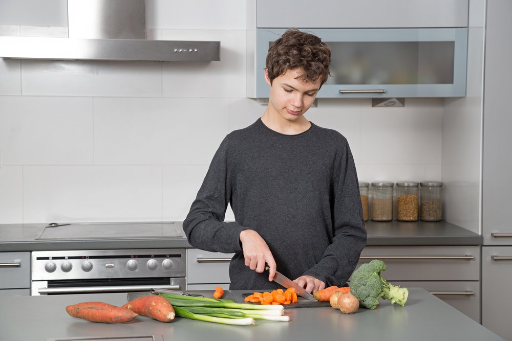 Adolescente cortando verduras. | Foto: Shutterstock