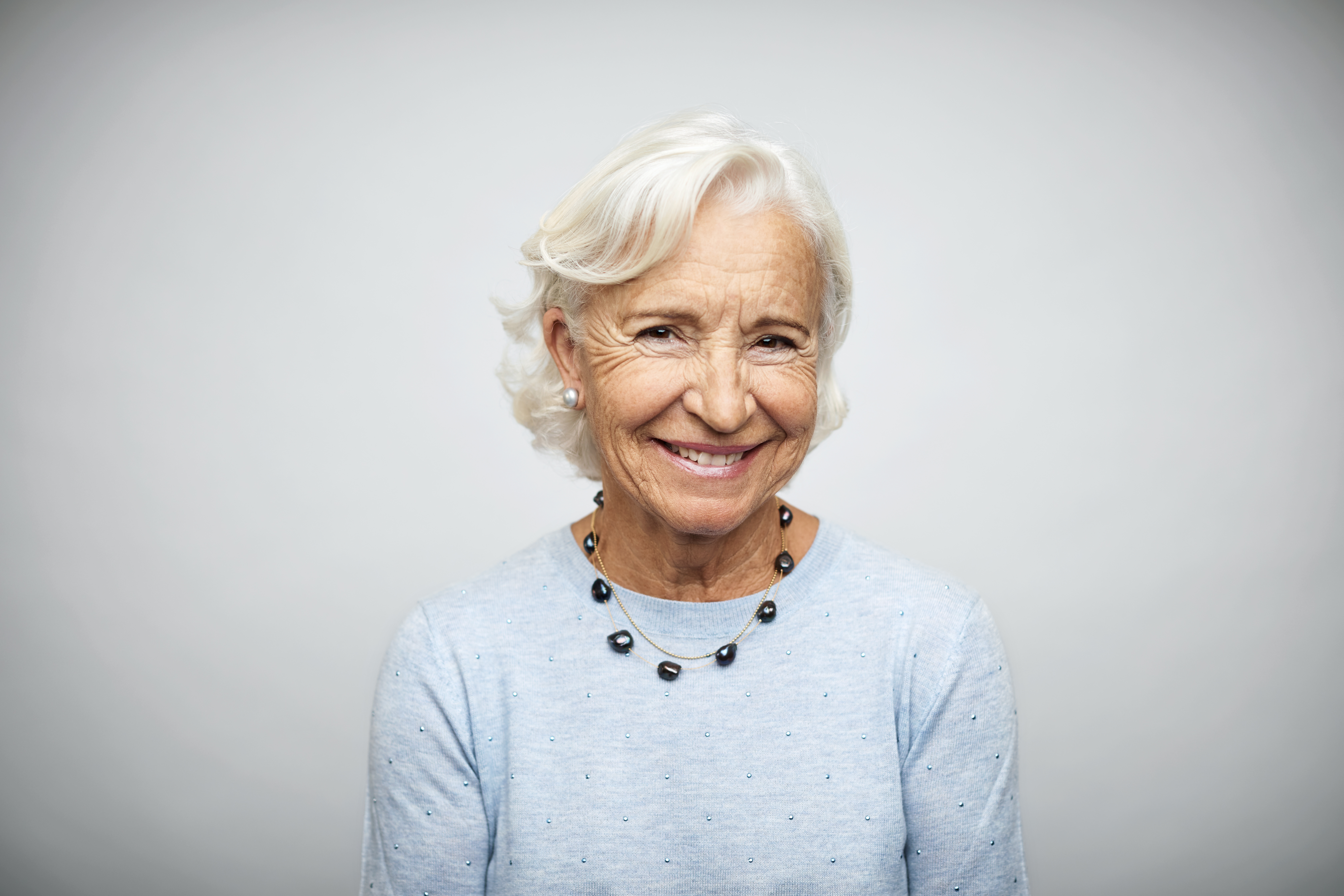 Elderly businesswoman smiling on white background | Source: Getty Images