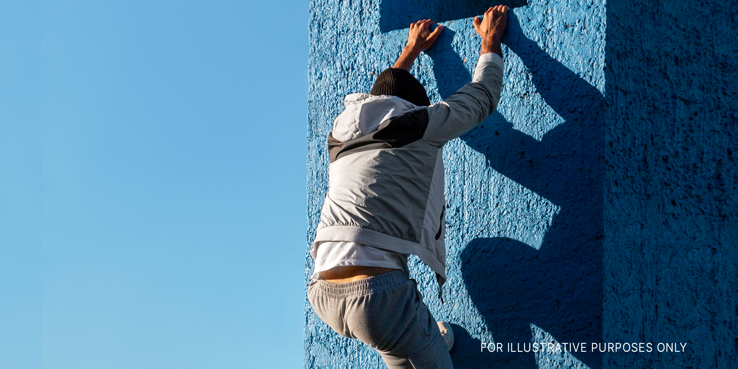 A man climbing a blue wall | Source: freepik.com