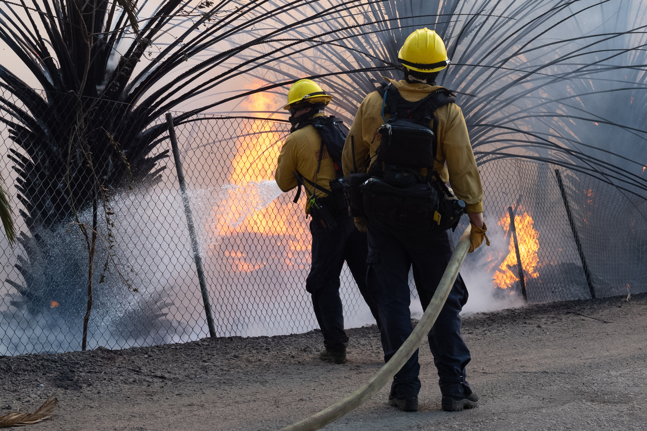 Firefighters dousing flames along Tierra Rejada road in Sim Valley, California on October 30, 2019 | Source: Getty Images