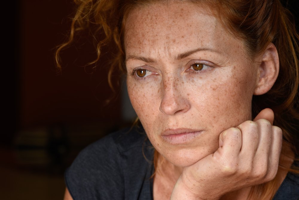 A portrait of a worried red haired woman. | Shutterstock