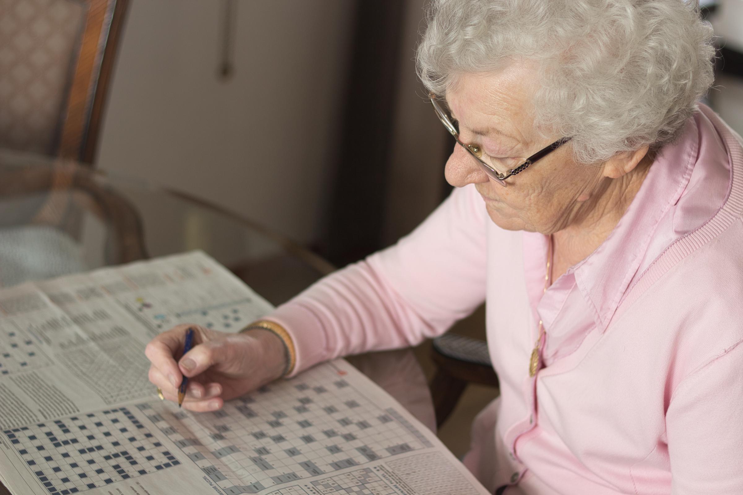 Senior woman solving a crossword puzzle | Source: Shutterstock