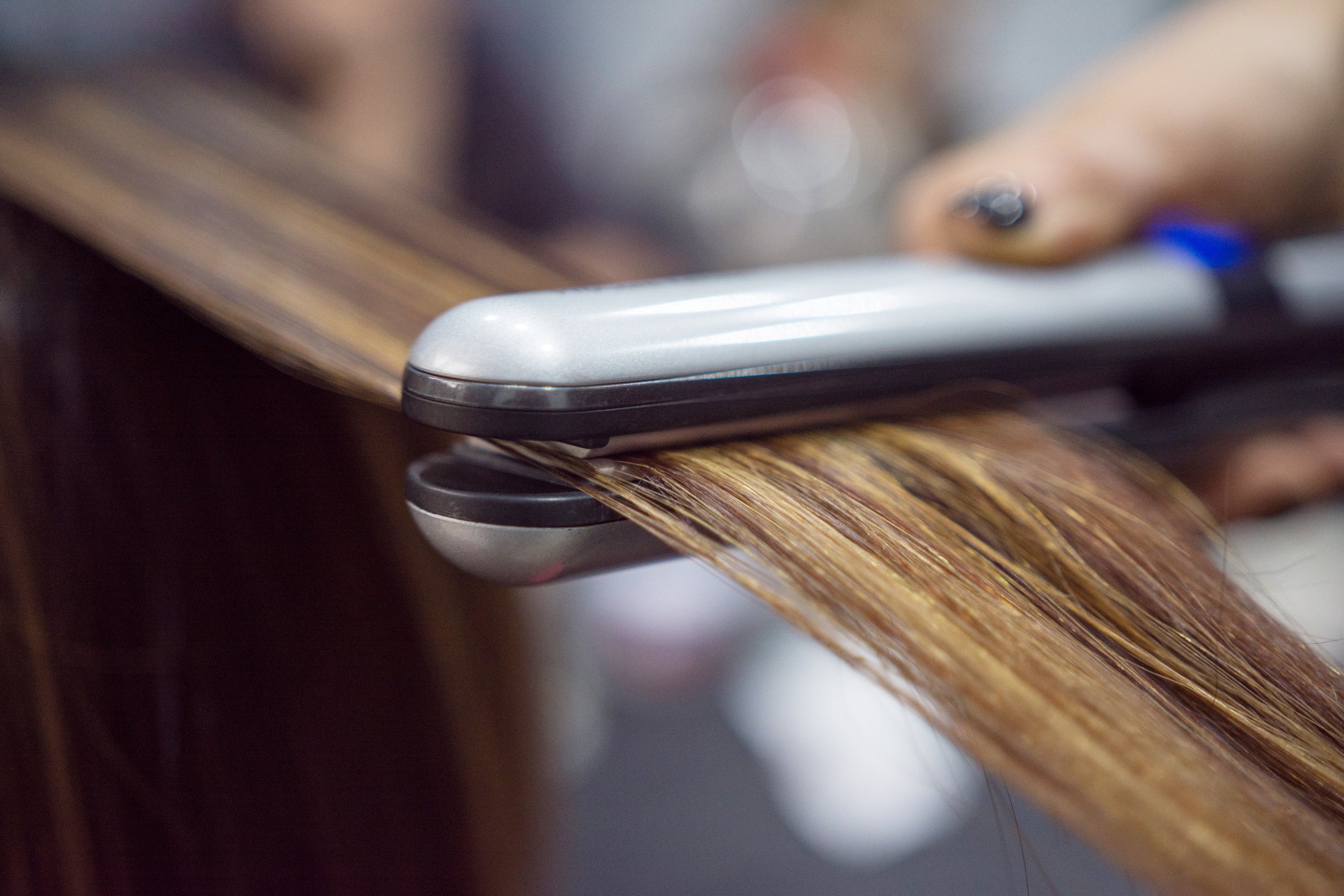 Friseur verwendet modernes Eisen, um die Haare der Kunden im Salon zu stylen | Quelle: Getty Images