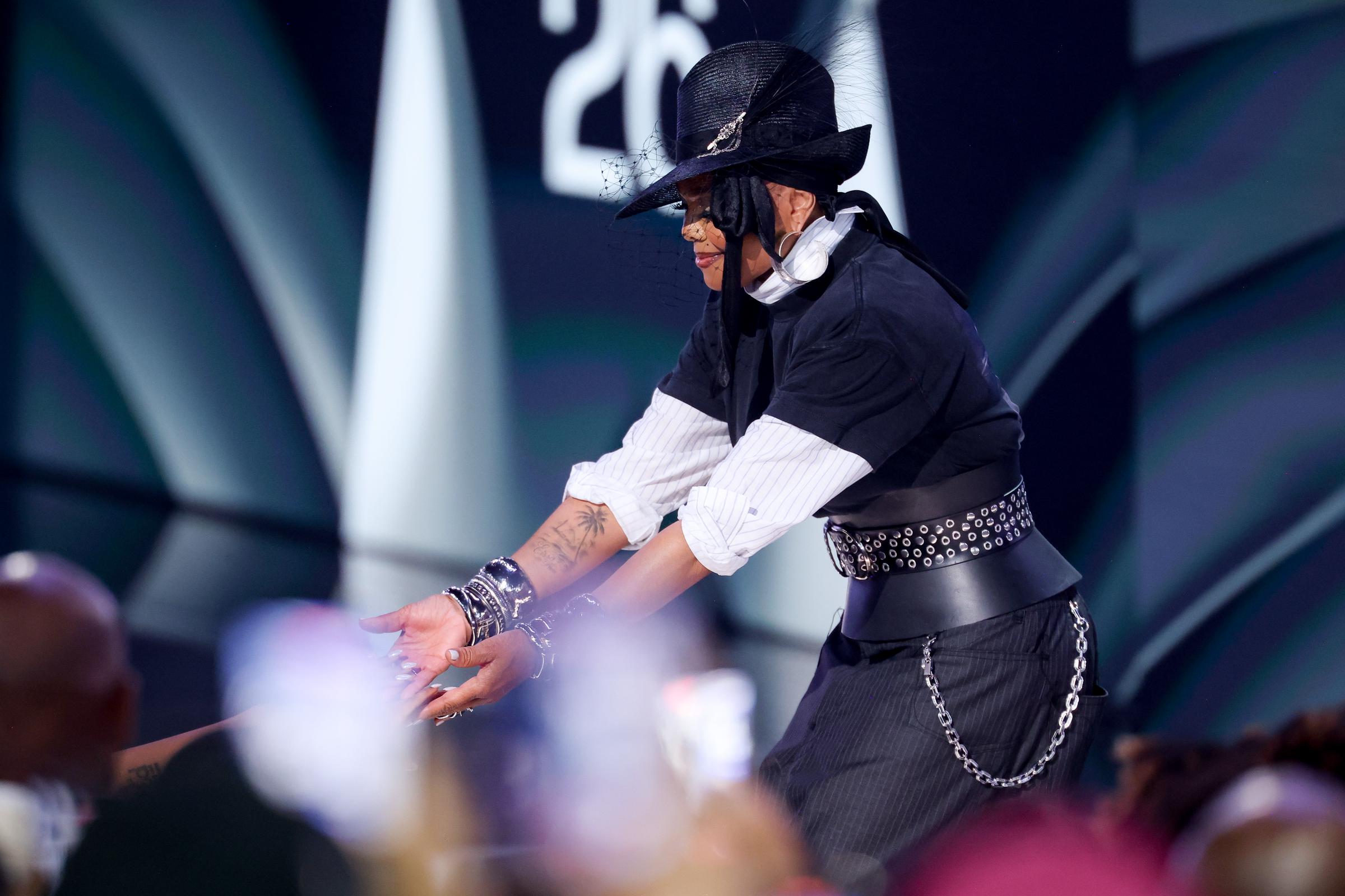 Janet Jackson's layered outfit, including a veiled fedora, corset belt, and graphic T-shirt, is seen as she presents the Icon of the Year Award at the 2026 BET Awards. | Source: Getty Images