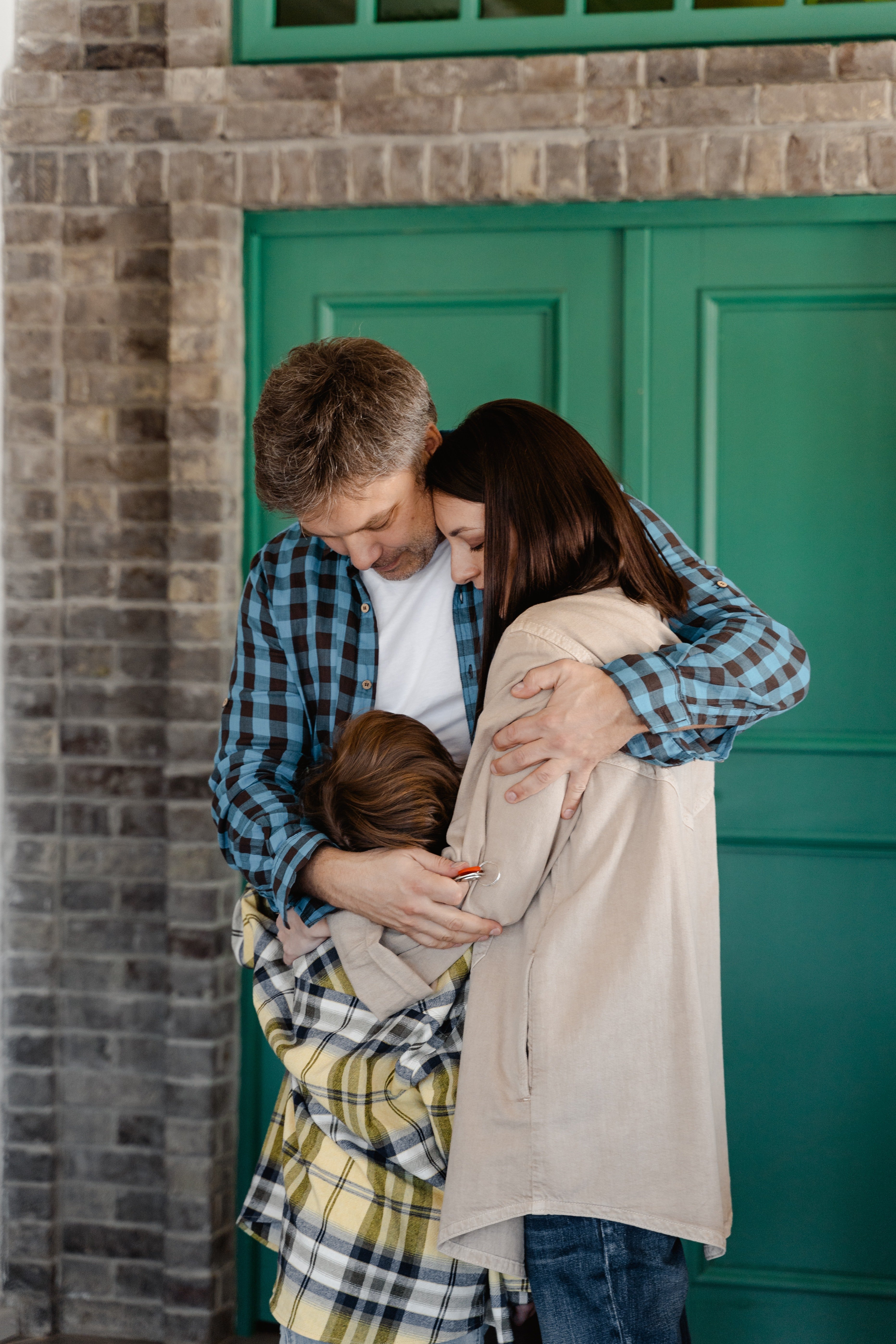 Unos padres abrazando a su hijo. | Foto: Pexels