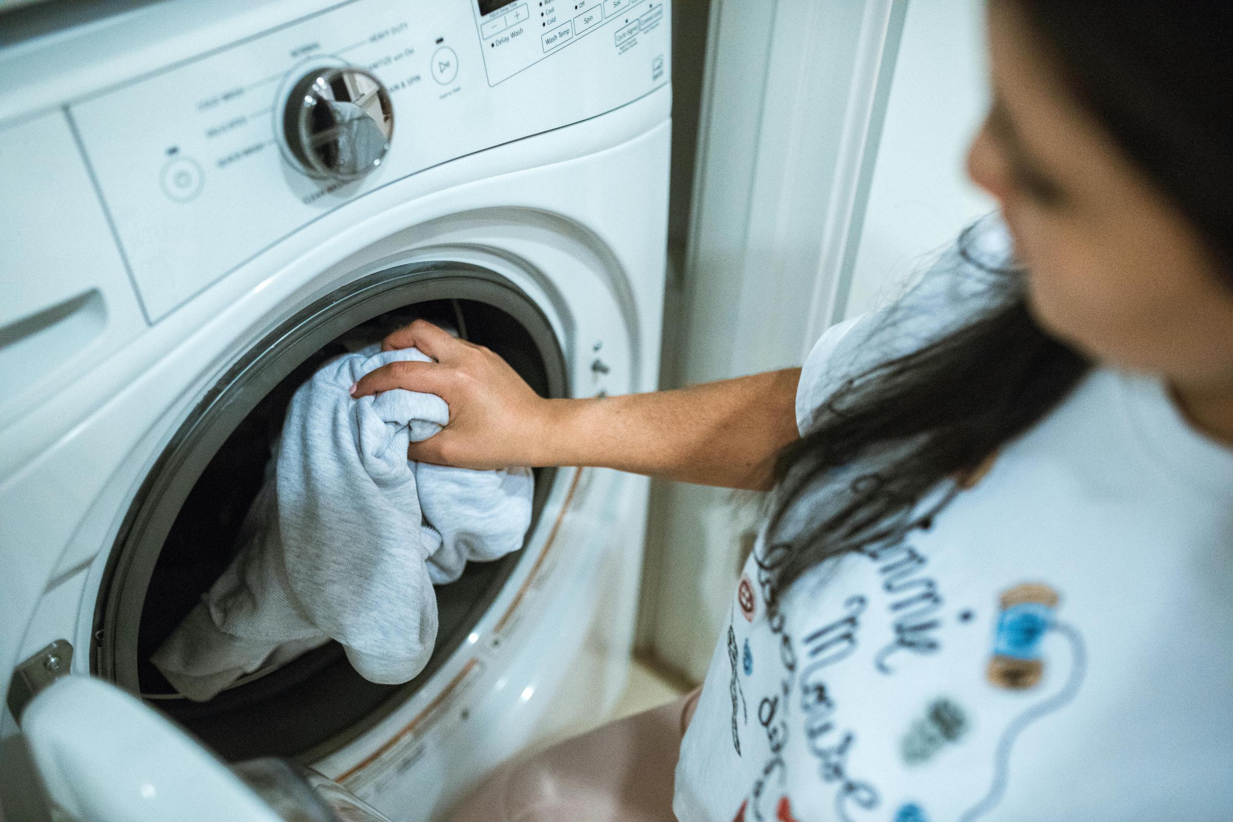 A woman putting her pajamas into the washing machine | Source: Pexels