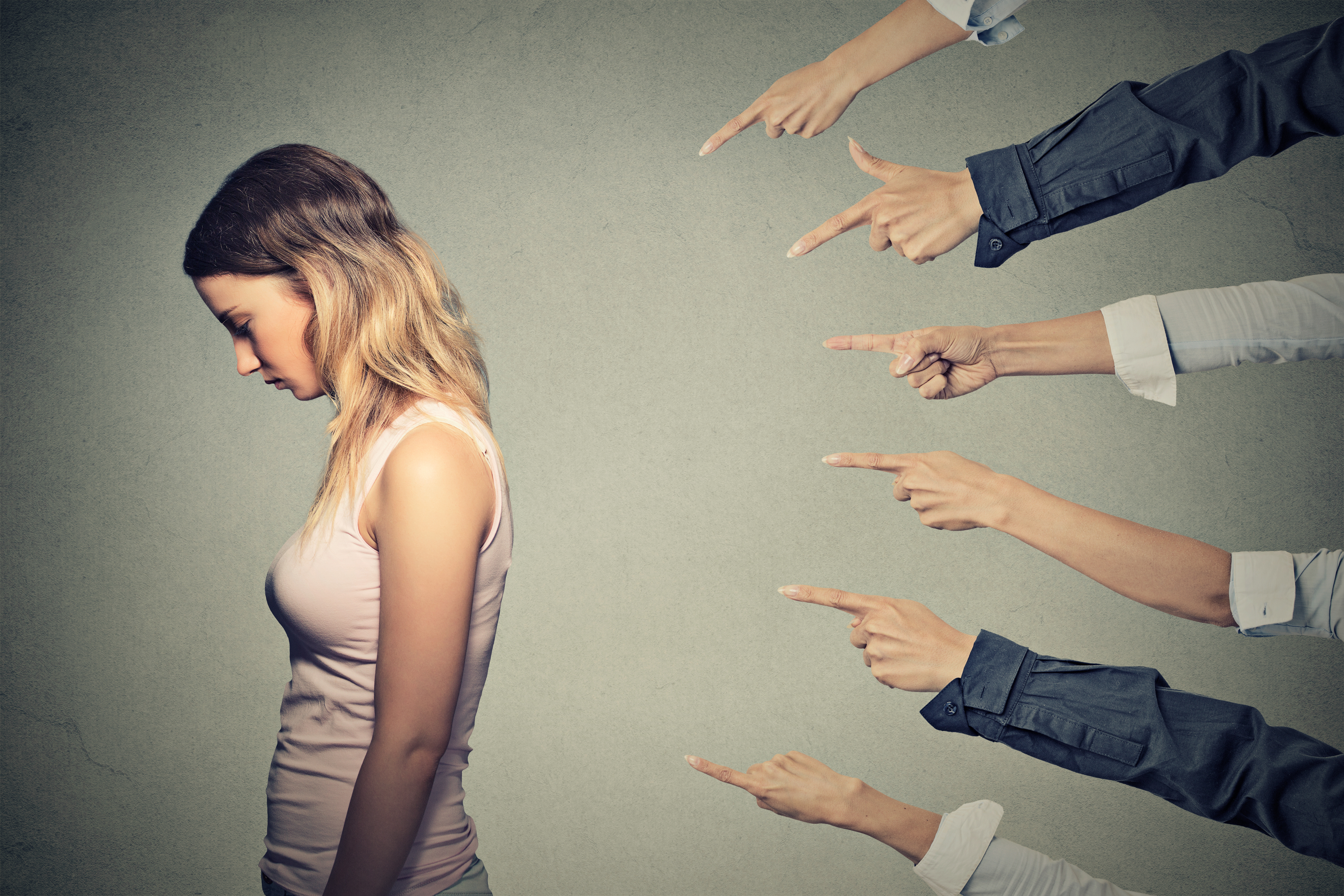 Many hands pointing at a young woman | Source: Shutterstock
