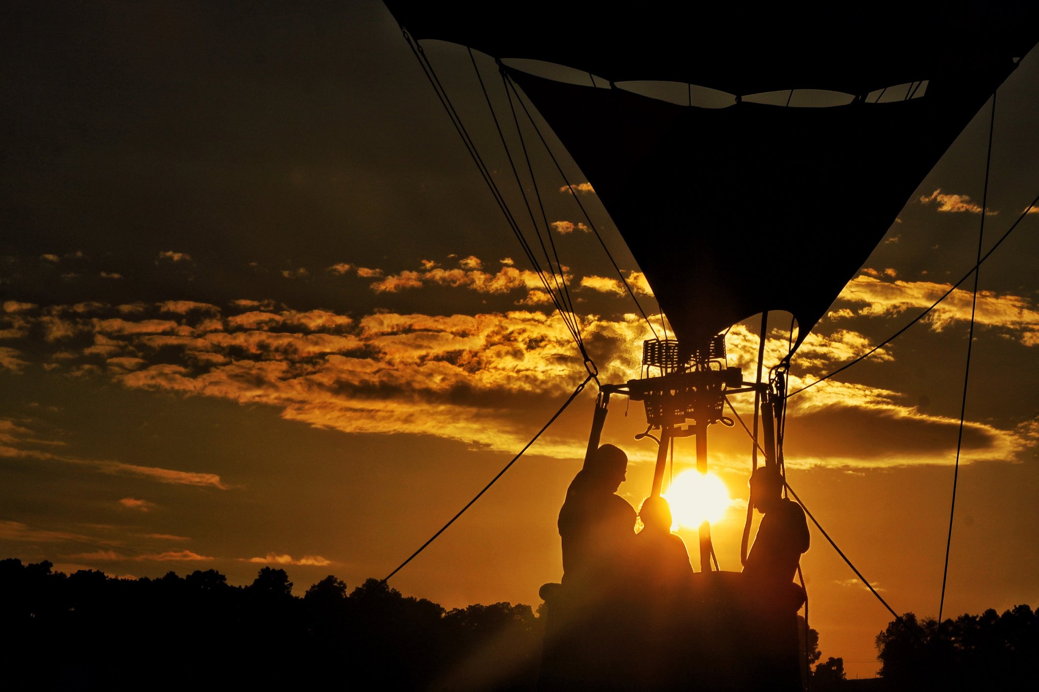 Weitwinkelaufnahme von Menschen in einem Heißluftballon am Himmel während des Sonnenuntergangs | Quelle: Getty Images