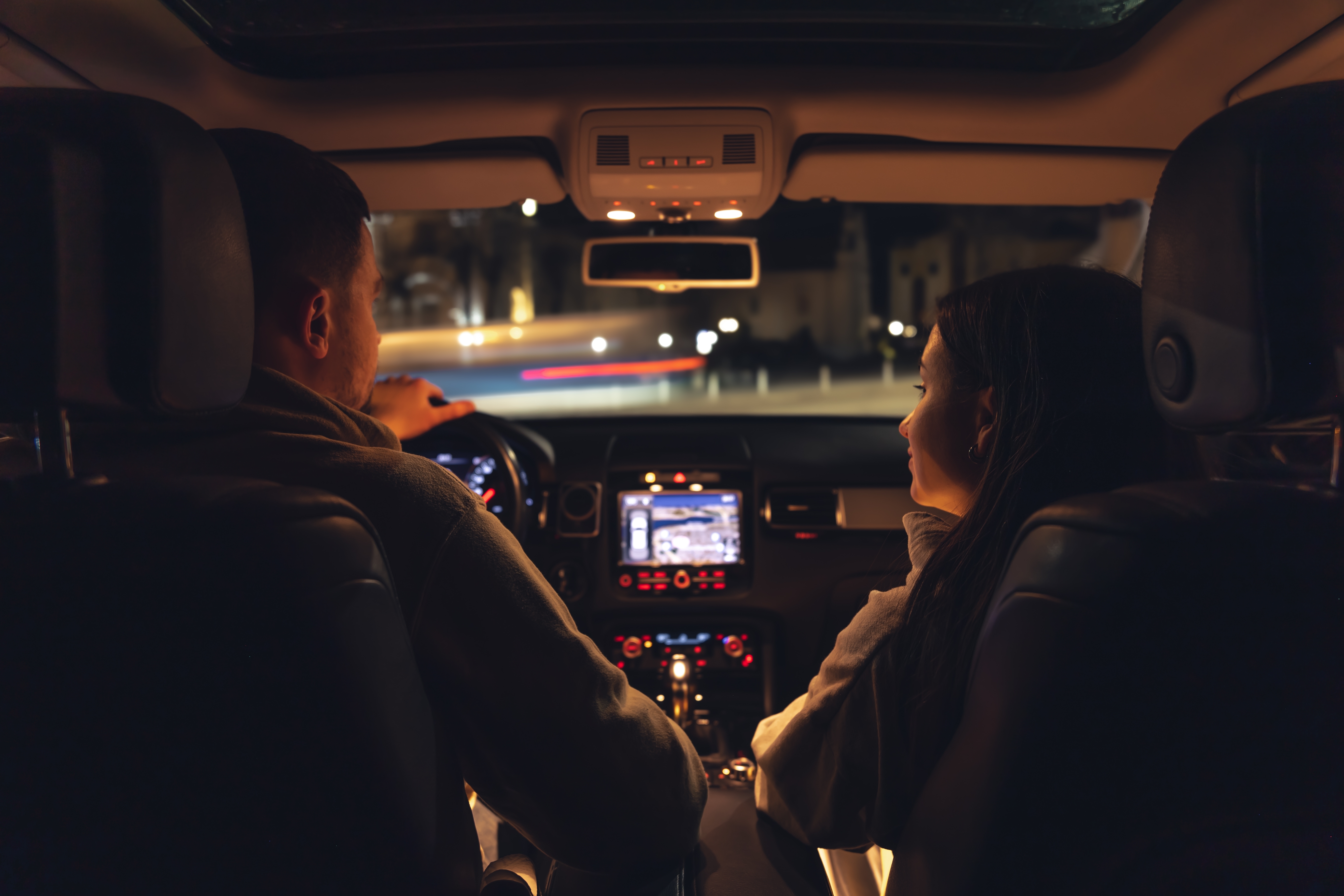 A mMan and a woman are driving in a car at night, the view from the car to the road. | Source: Shutterstock
