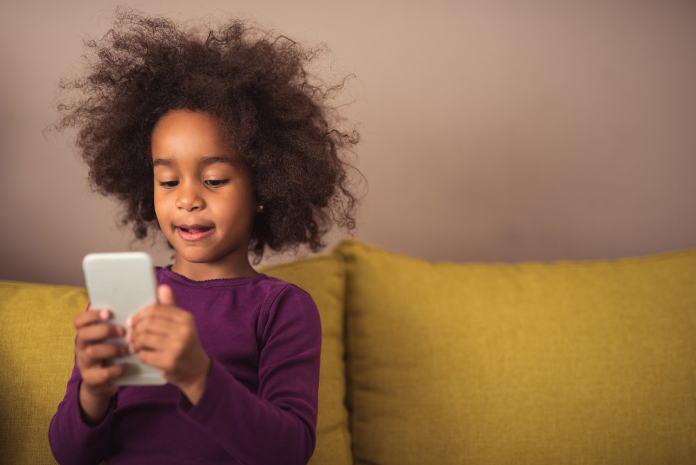 Little girl using cellphone. | Photo: Shutterstock