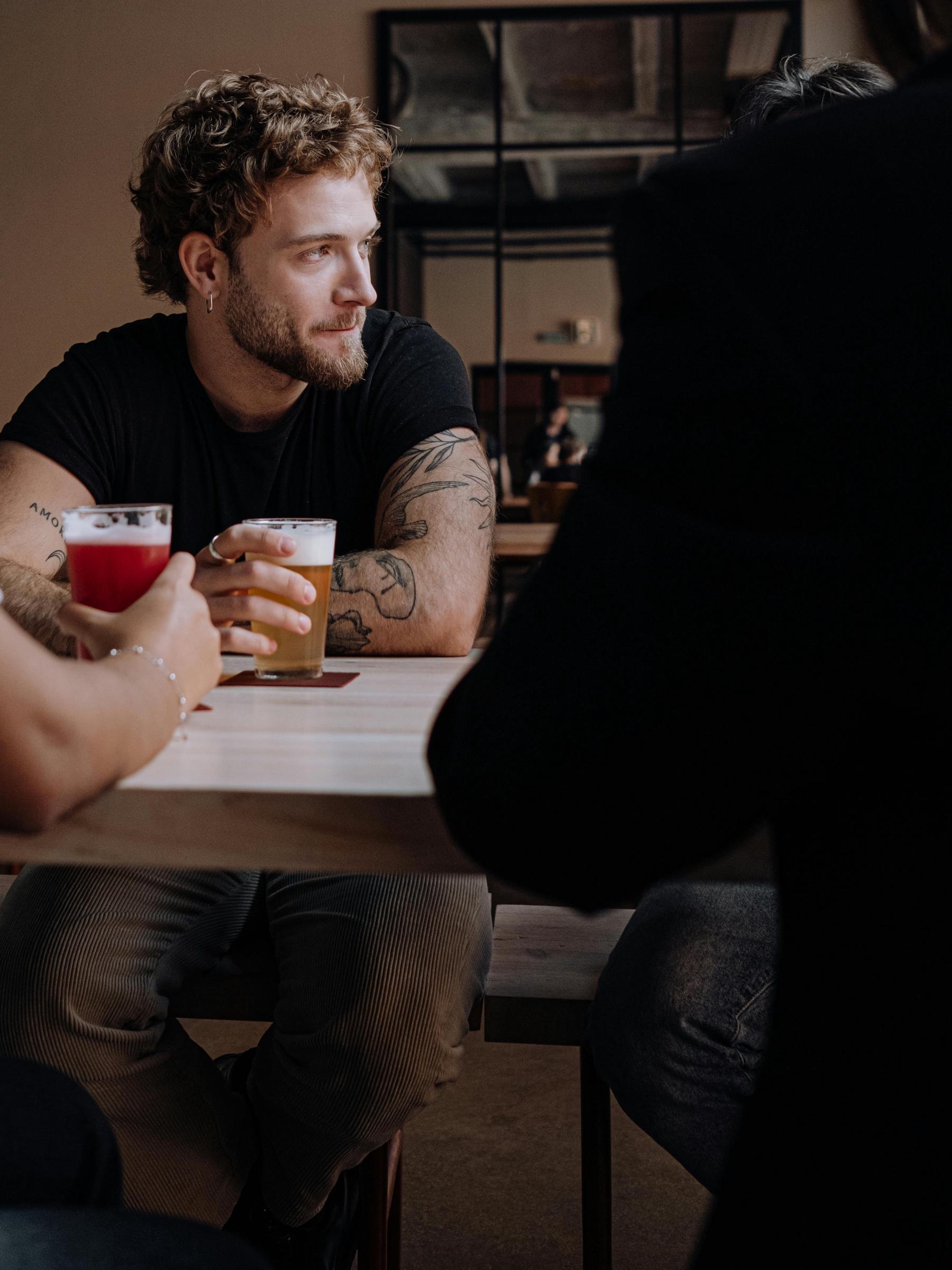 A man glancing aside, seated with a beer at hand | Source: Pexels