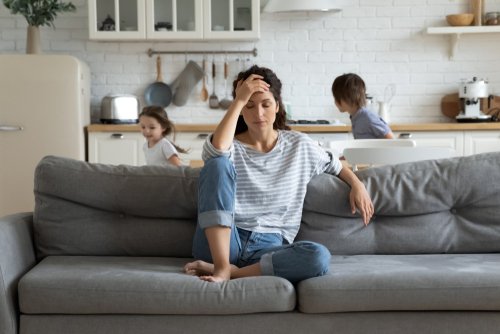 Gestresste Mutter auf der Couch mit ihren Kindern | Quelle: Shutterstock