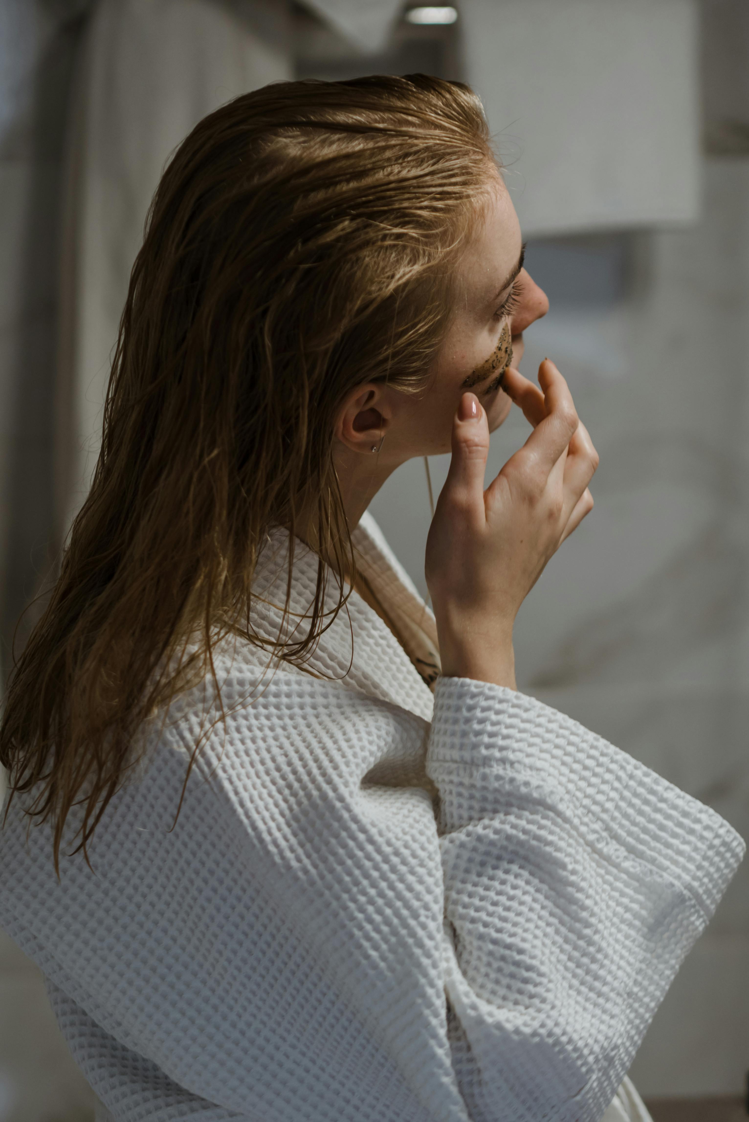A woman applying facial products after taking a shower | Source: Pexels