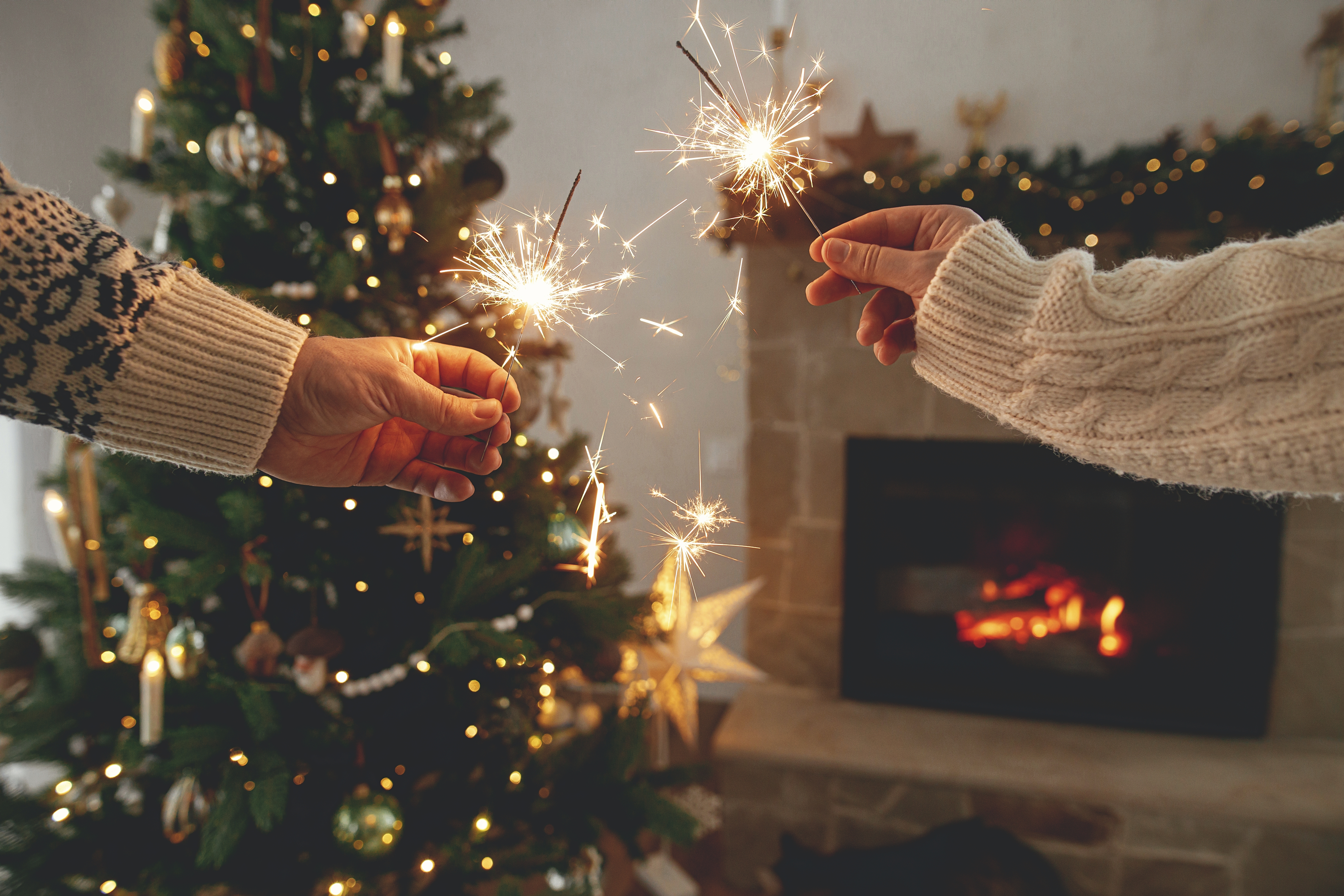 Two people burning sparklers near a Christmas tree | Source: Shutterstock