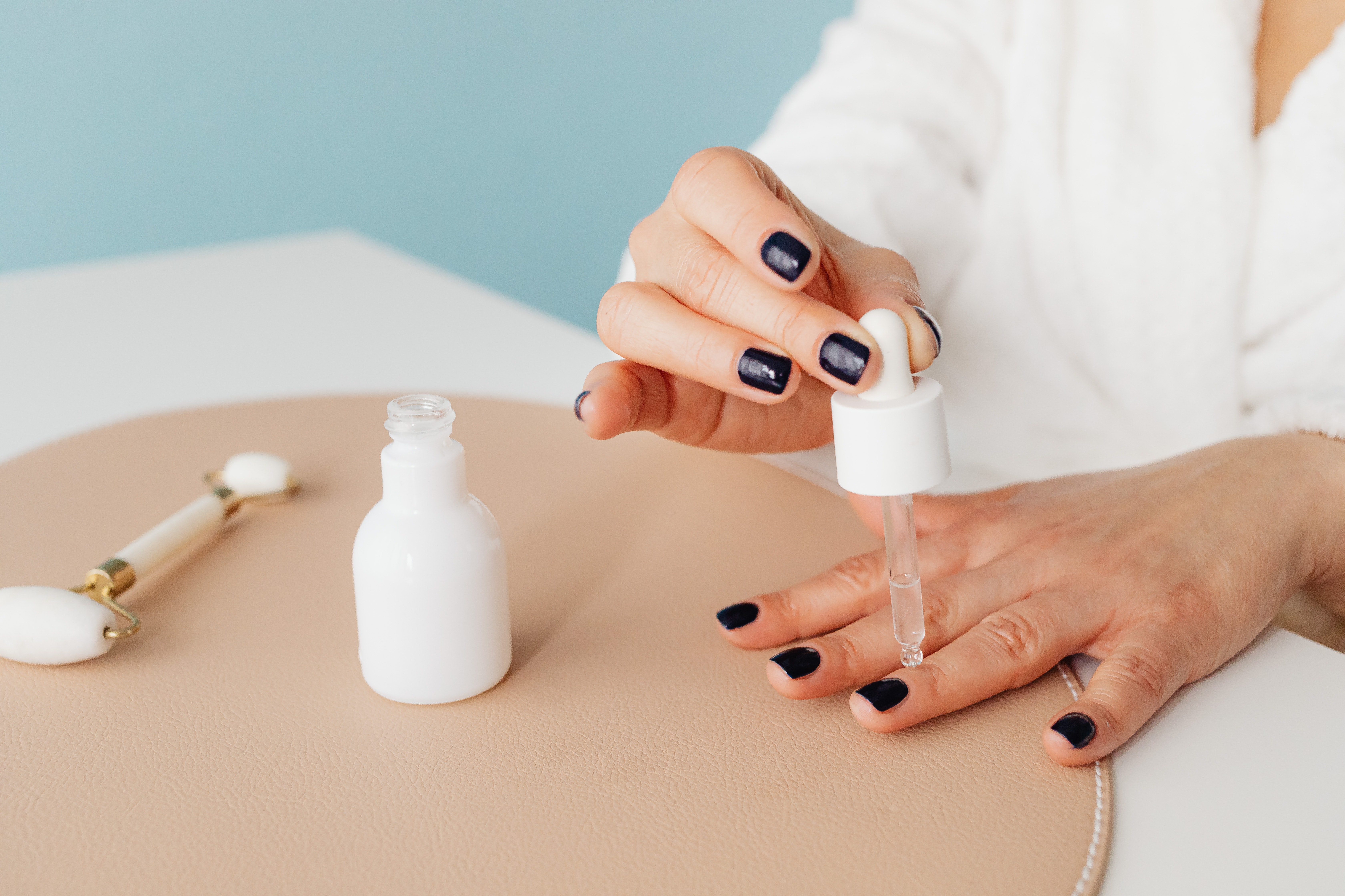 A woman applying oil onto her nails. | Source: Pexels